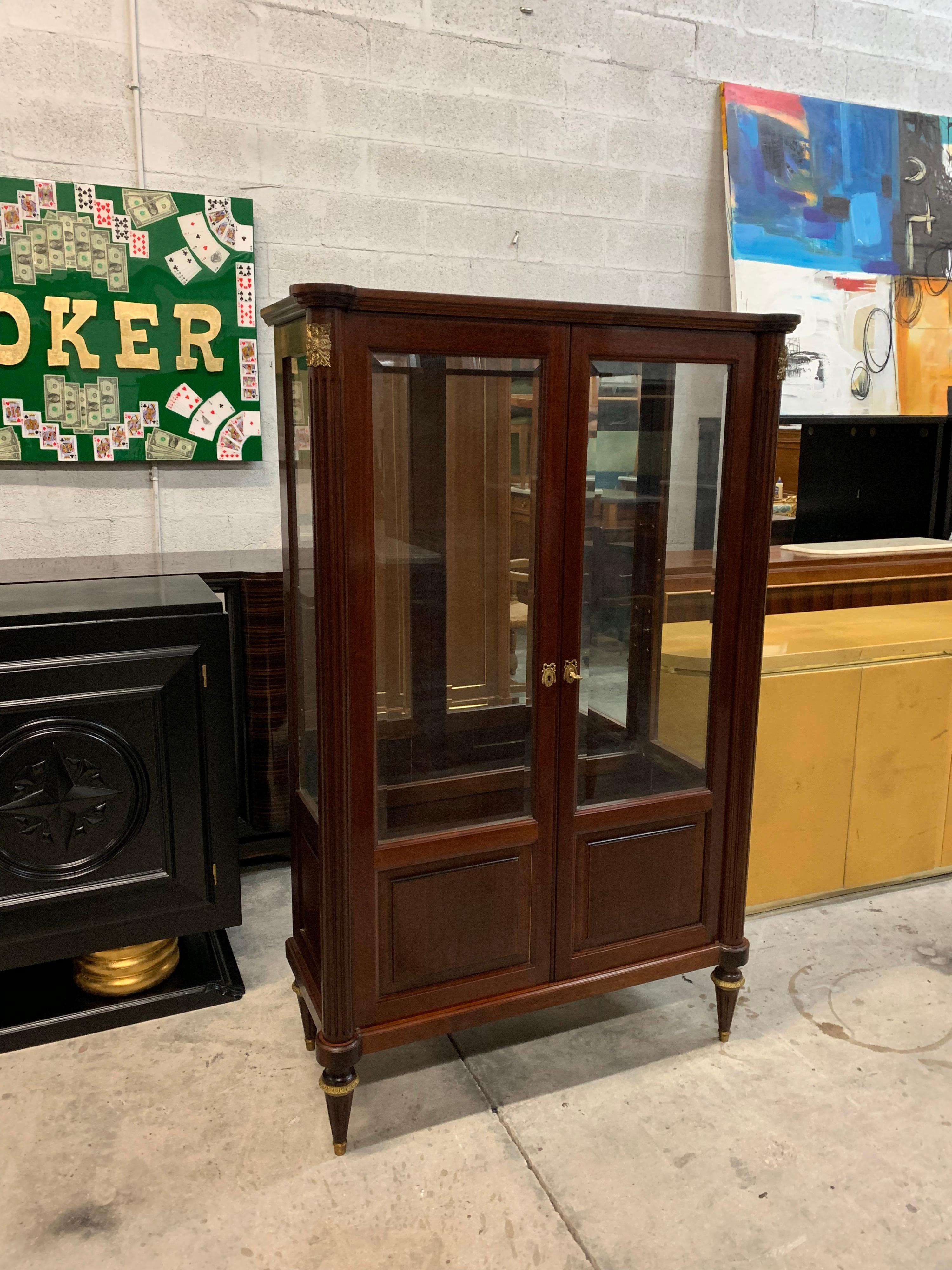 French antique Louis XVI style bookcase / vitrine 1910s made of mahogany, the mahogany wood has been finished with a French polished high luster inside and outside, It has two-door with beveled glass and a working lock and key. The mirrored interior