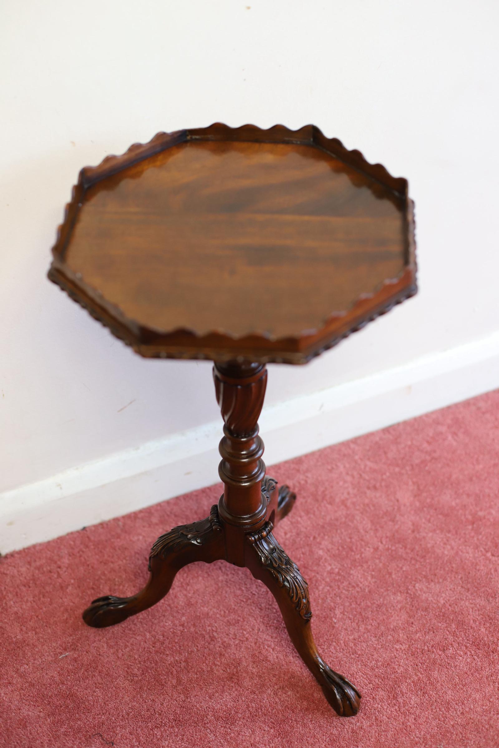 We delight to offer for sake this English mahogany wine table, George II style, 20th century, the octagonal top with beaded edge and scalloped gallery, on written and turned column to three carved legs, ball and claw feet, some repairs to gallery