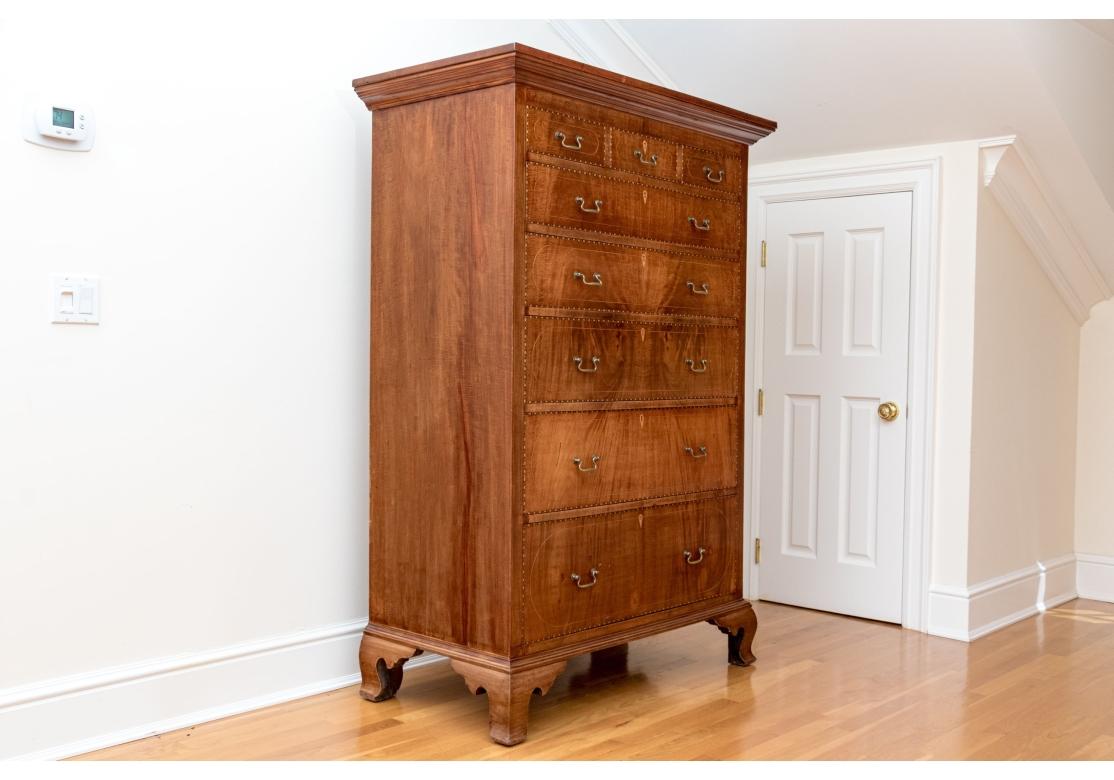 A particularly noteworthy Tall Antique Mahogany Chest with fine form, dove-tail drawer construction, original brass pulls and extensive inlay.  On four carved feet, the chest with five long graduated drawers with two brass swing handles and inlaid