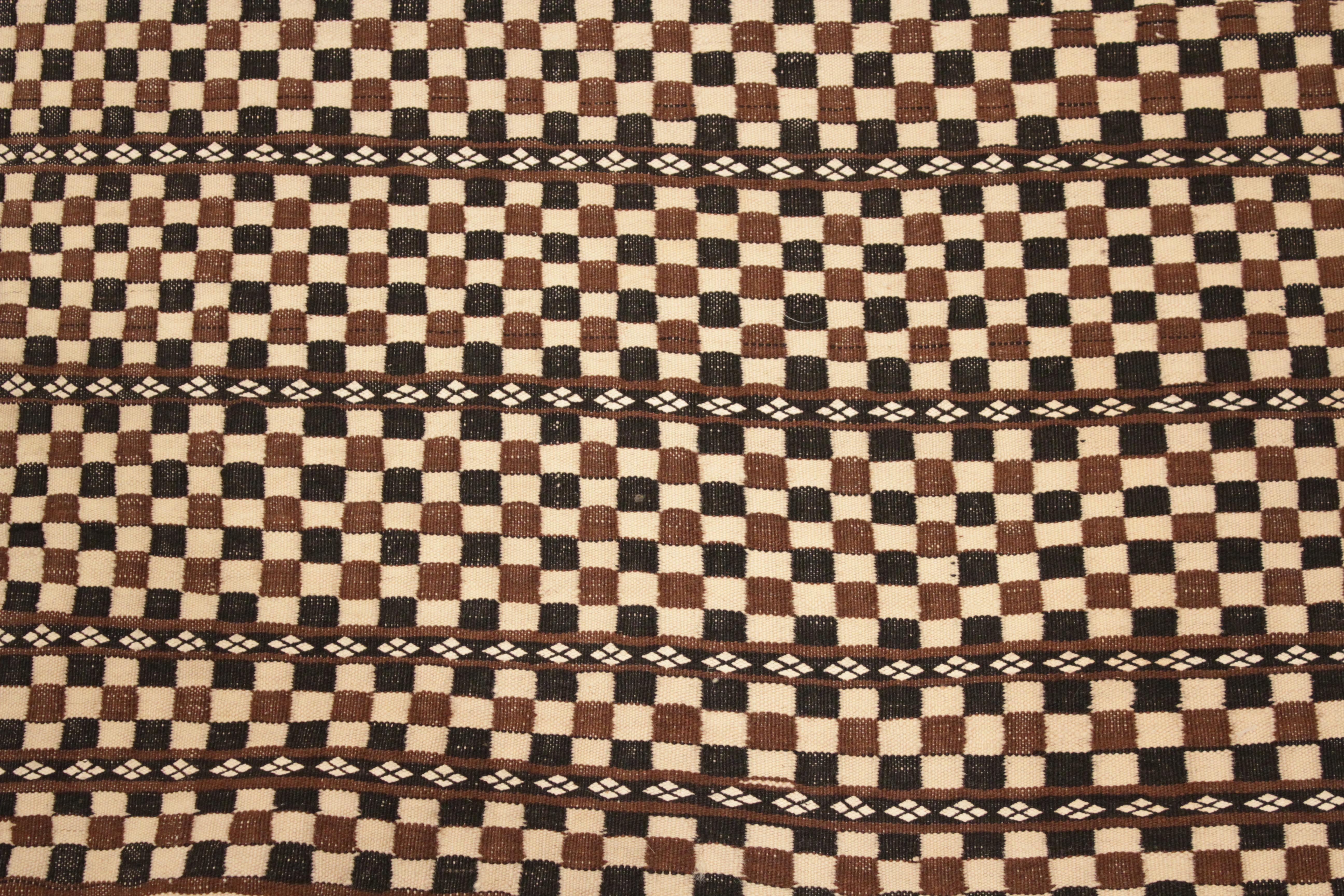 A very elegant and refined Berber weaving, composed of an honeycomb arrangement of ivory, chocolate brown and black squares contained within horizontal compartments. The extreme fineness of weave and the uniqueness of the design allows us to date