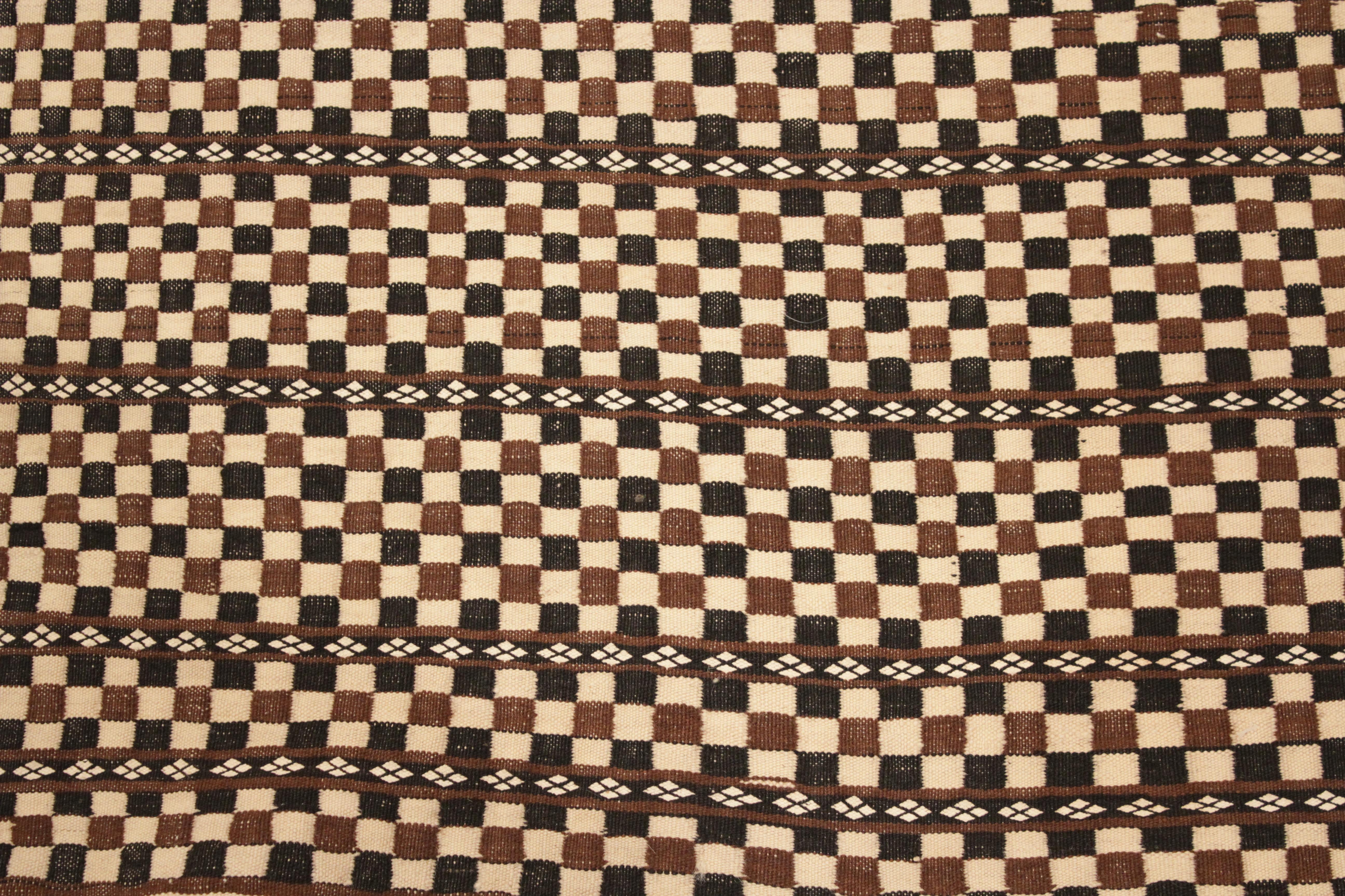 A very elegant and refined Berber weaving, composed of an honeycomb arrangement of ivory, chocolate brown and black squares contained within horizontal compartments. The extreme fineness of weave and the uniqueness of the design allows us to date