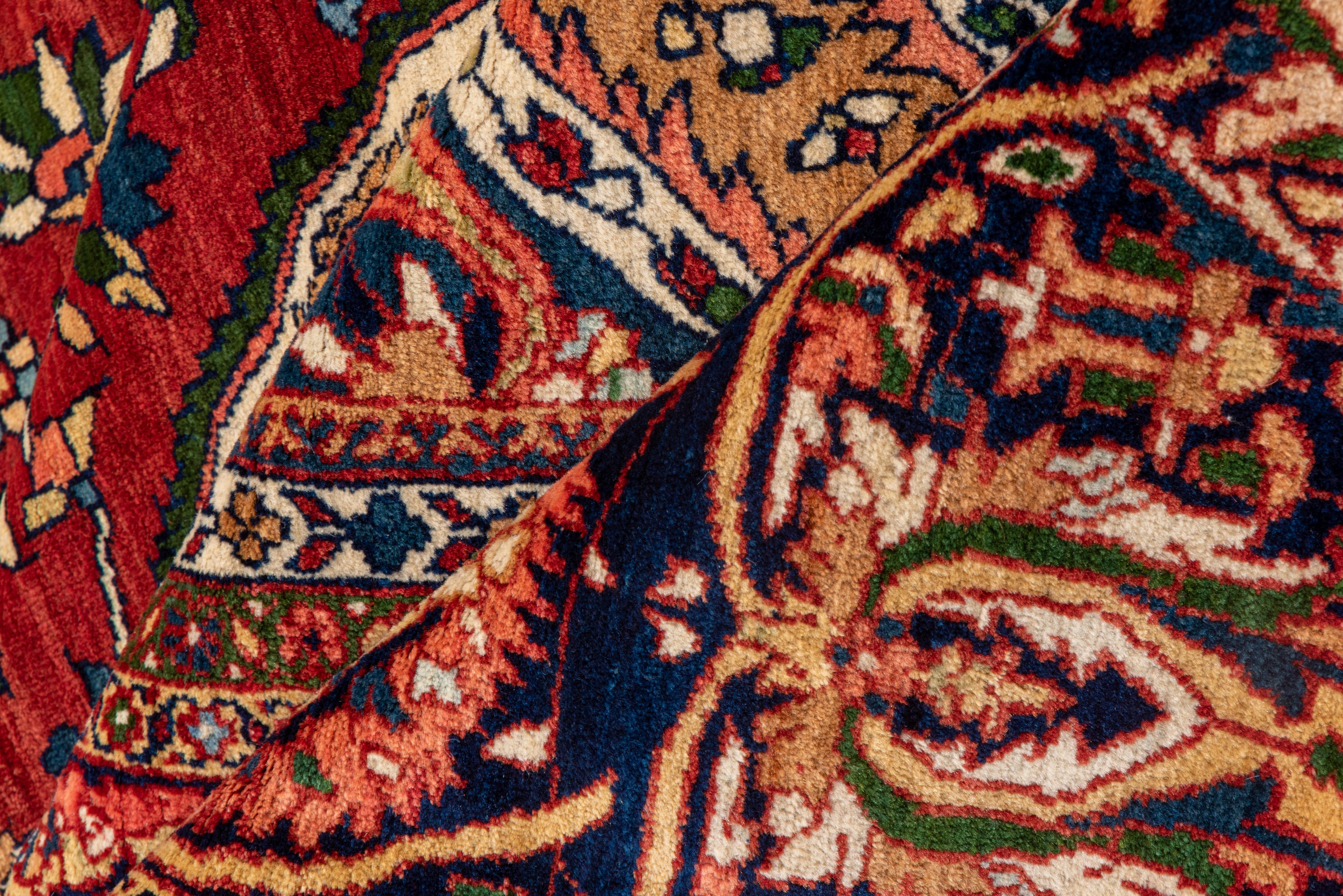 Questo tappeto di palazzo della Persia occidentale, finemente tessuto, presenta un campo rosso rubino, un medaglione blu ceruleo e angoli avorio, il tutto con piccoli dettagli ovunque. Bordo principale blu scuro con foglie enfatiche a forma di C che
