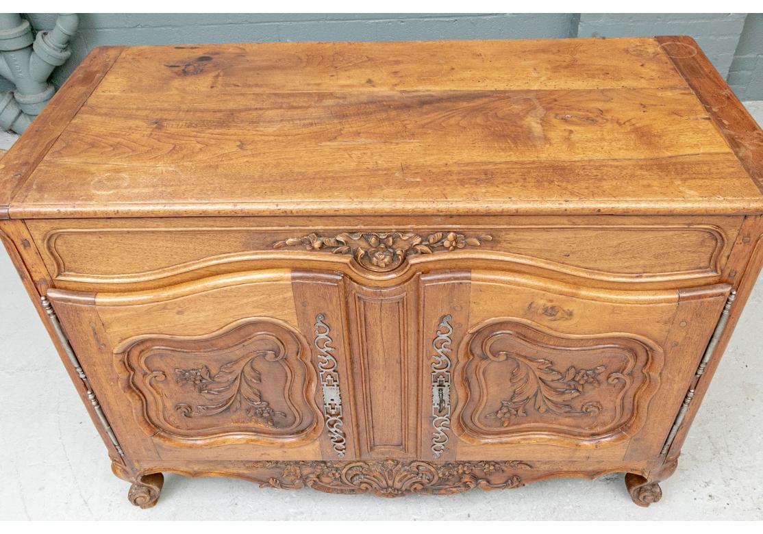 An authentic and Provincial French two-door buffet in traditional form. With a banded top over a carved, shaped and recessed frieze with flowers. The Lower double doors with shaped recessed panels and carved flowers on scrolled stems. With classic