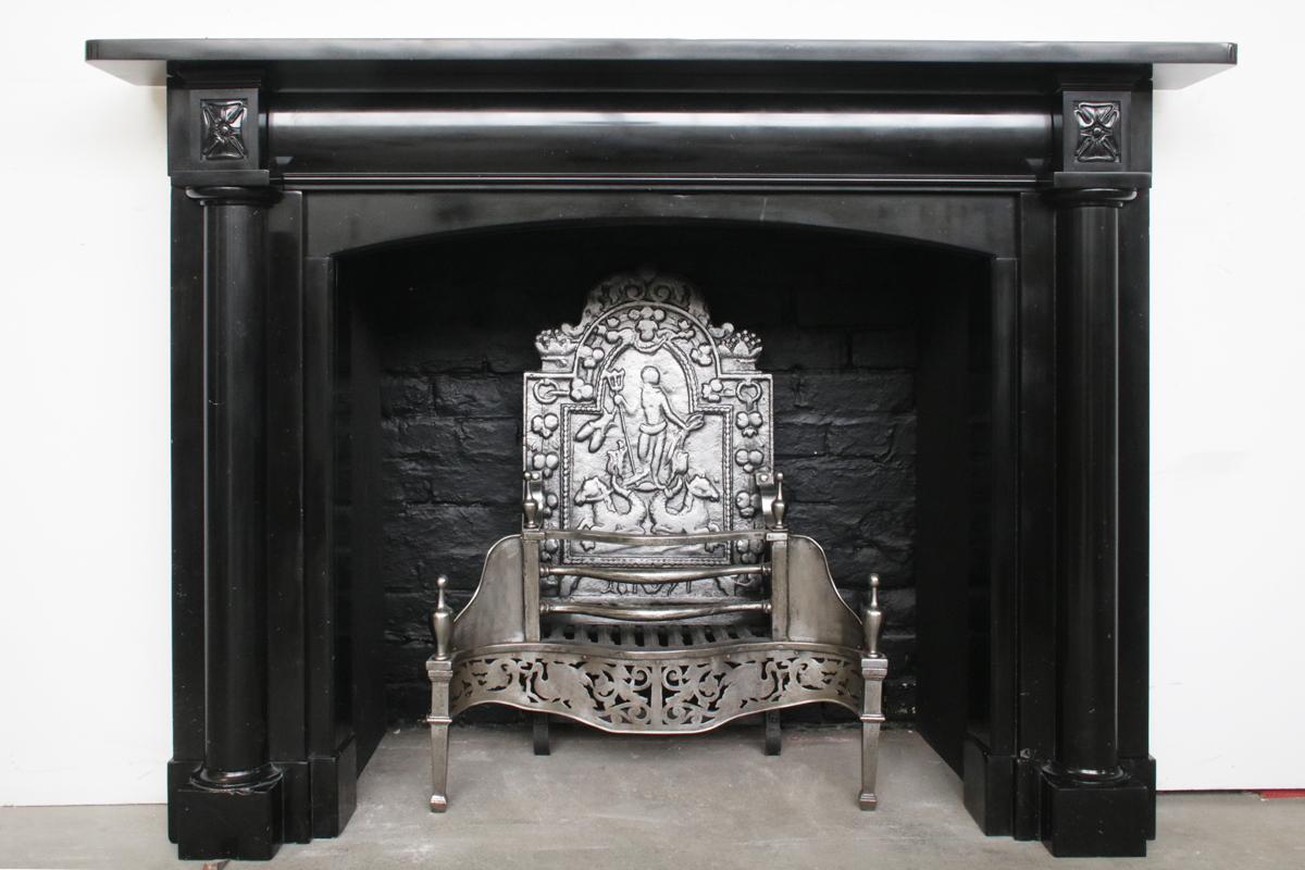 Fine antique Regency chimneypiece in Kilkenny black marble, with full length pillars terminating in well carved capital blocks, flanking a slow arched cushion moulded frieze, Circa 1830.

Pictured with an original cast iron and steel fire basket,