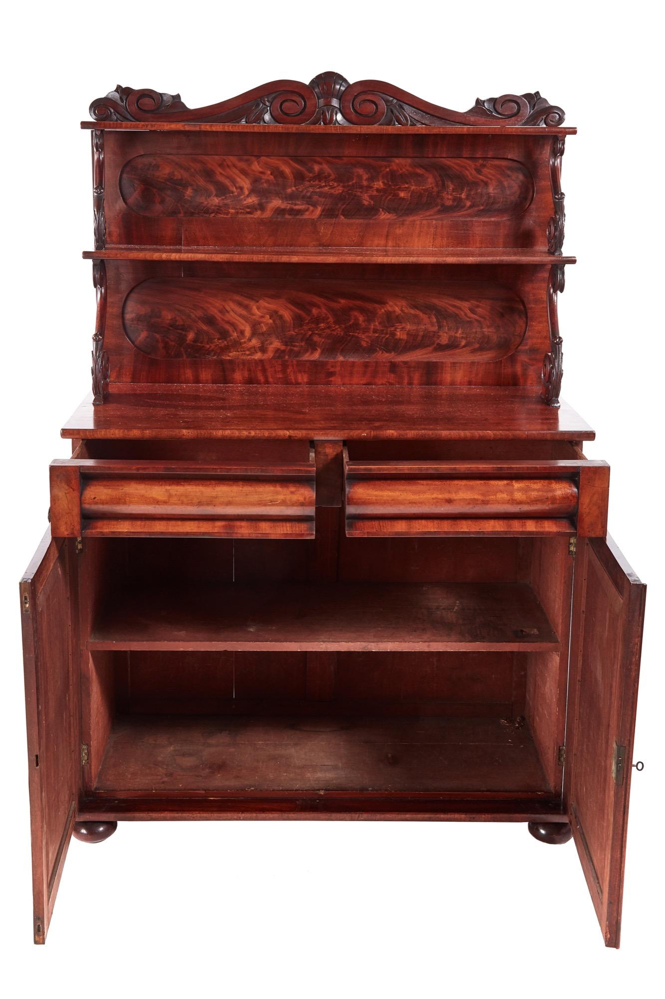 Fine Regency antique carved mahogany chiffonier, beautifully carved back with two shelves and carefully carved attractive supports. The base has two shaped frieze drawers with two flame mahogany doors with arced panels, pretty carved corbels, one