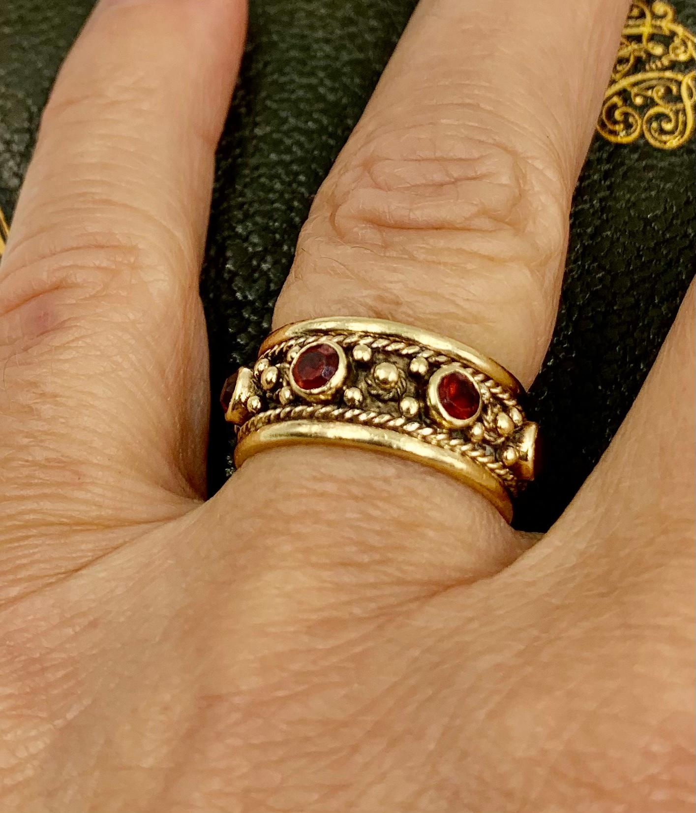 Ornate Renaissance style 14K yellow gold garnet set band ring
Late 19th Century
Marks: Marker's mark A within a shield, 14K
Technique: Twisted gold wire work, granulation, cullet set gemstones
Size: 5.75 US
Very Good Condition

Very fine quality,
