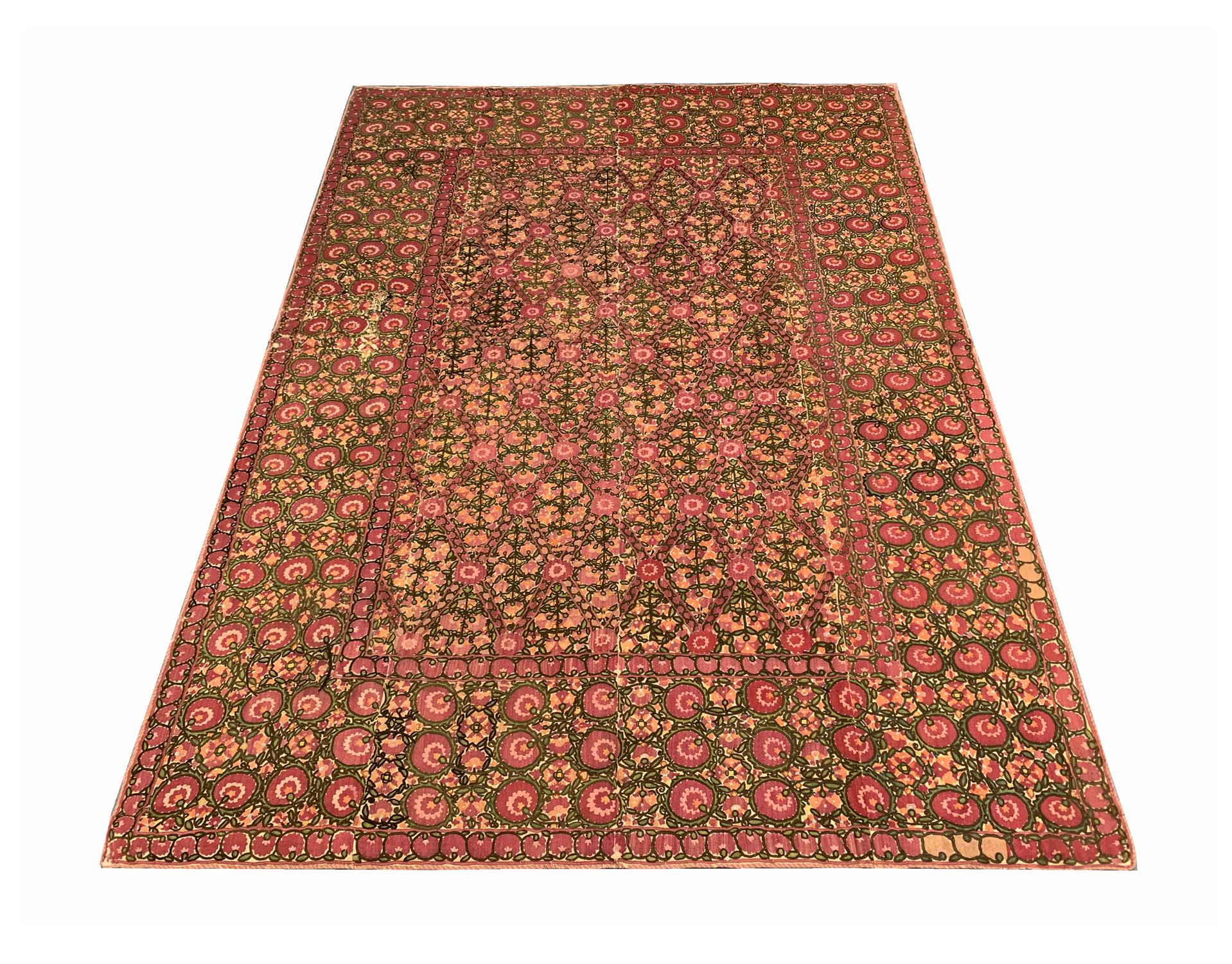 This fine handwoven wool antique textile was woven in Tajikistan in the 1900s. The central design features a highly decorative floral design, intricately woven with delicate flowers. Woven with accents of pink, green, orange and ivory. Both the