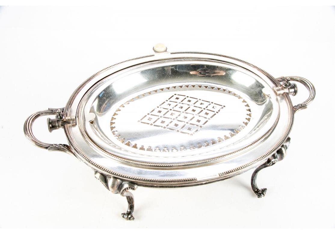 A swivel dome top server decorated with a chased crown and crest on the front of the lid, and florals on the back. With a separate pierced warming plate inside and a bone or synthetic bone lift knob. There is a Bell mark on the lower interior tray.