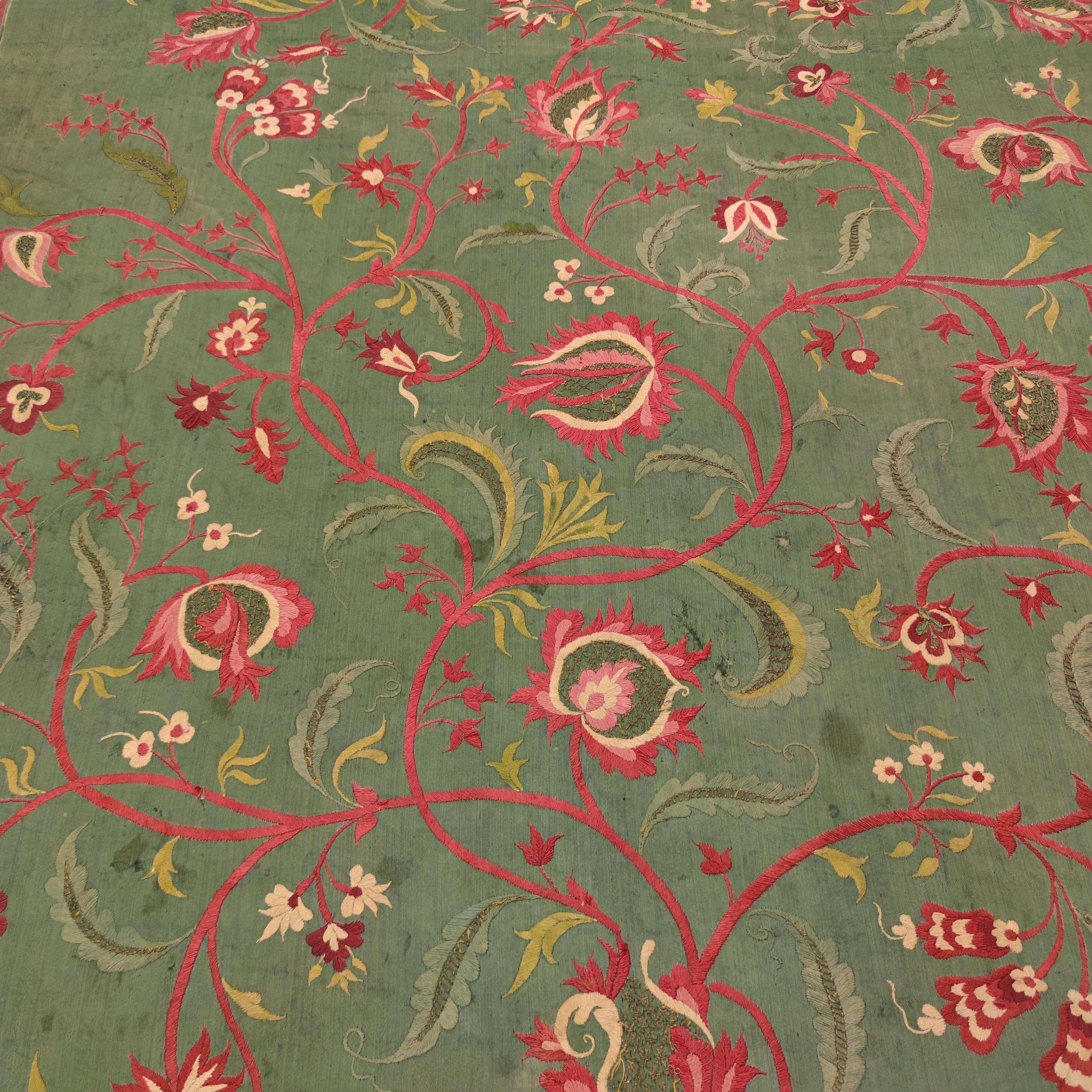 Probably commissioned for the Portuguese market, this elegant silk embroidery, complete of selvedges, shows a blossom of various flowers and leafs embellishing a teal blue-green background. The syncretism created by the the skilful drawing of the