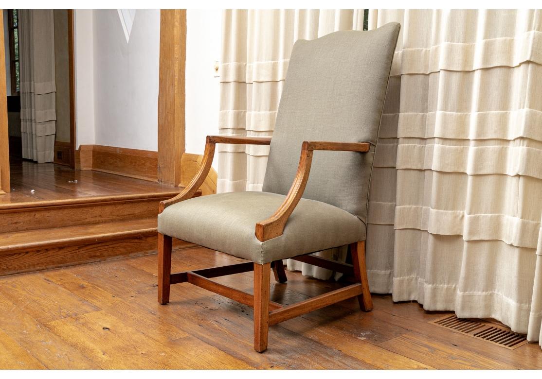 Un fauteuil ancien particulièrement raffiné avec un bois au ton miel doux et une forme élégante. Avec une haute traverse en forme de crête et des supports d'accoudoir inclinés et sculptés. Il repose sur des pieds avant carrés avec des incrustations