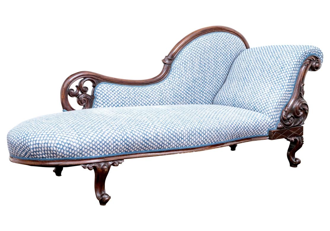 An elegant and  fine mahogany reclaimer upholstered in a blue and white woven fabric with geometric design accentuated with contrasting flue double welting. The reclaimer with beautifully carved mahogany frame with acanthus leaf motifs, a scrolling