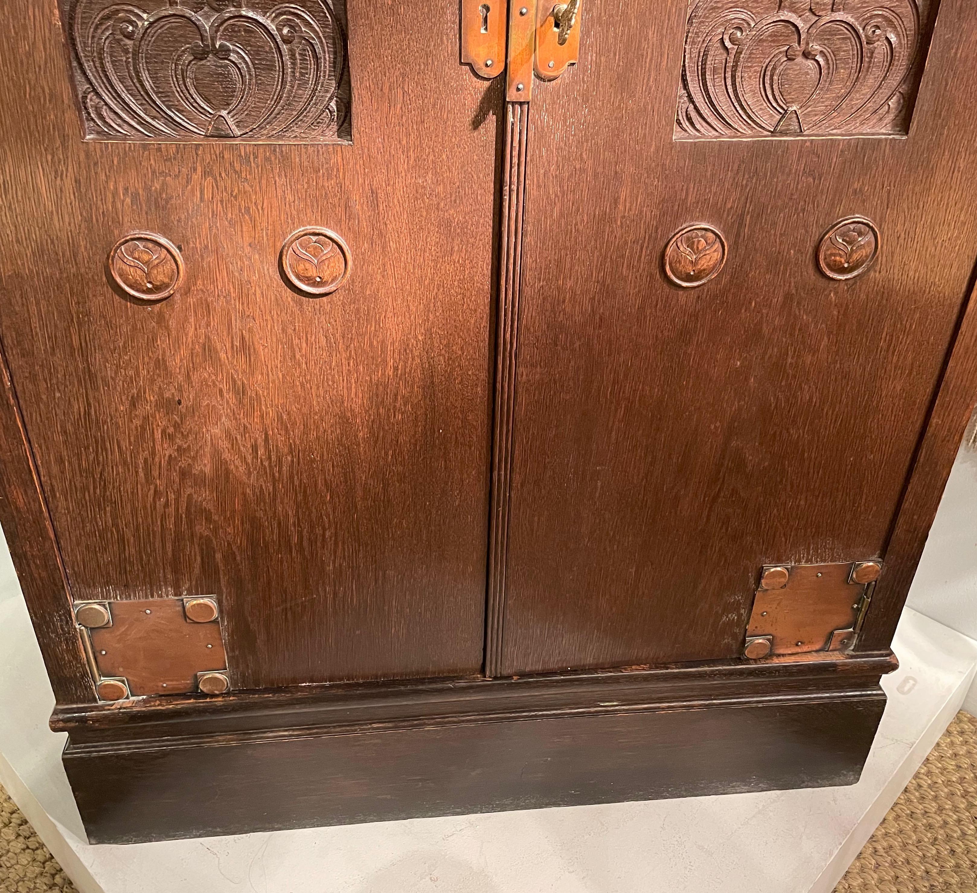 Feiner Kleiderschrank in Cutaway-Form mit zwei abgeschrägten oberen Türen aus Buntglas. 
Viele geschnitzte Kupferdetails und Originalschlüssel.
Vier Einlegeböden und eine Schublade.
Wahrscheinlich Wien um 1890.