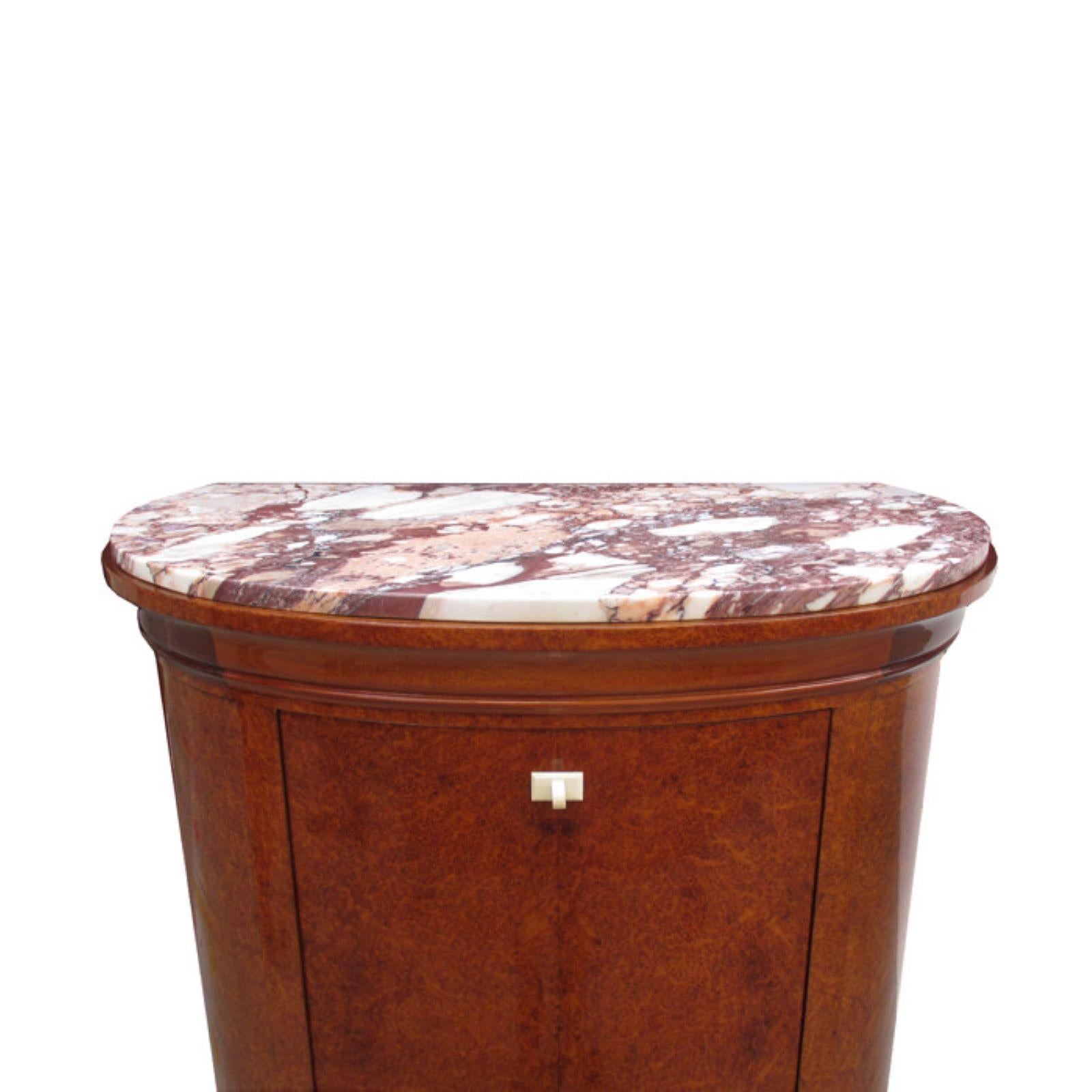 Un fino mueble bar Art Decó.
Amboyna con tapa de mármol y escudos de hueso.
Interior con superficies espejadas, detalles de bronce patinado
y estantes de cristal. Interior iluminado.