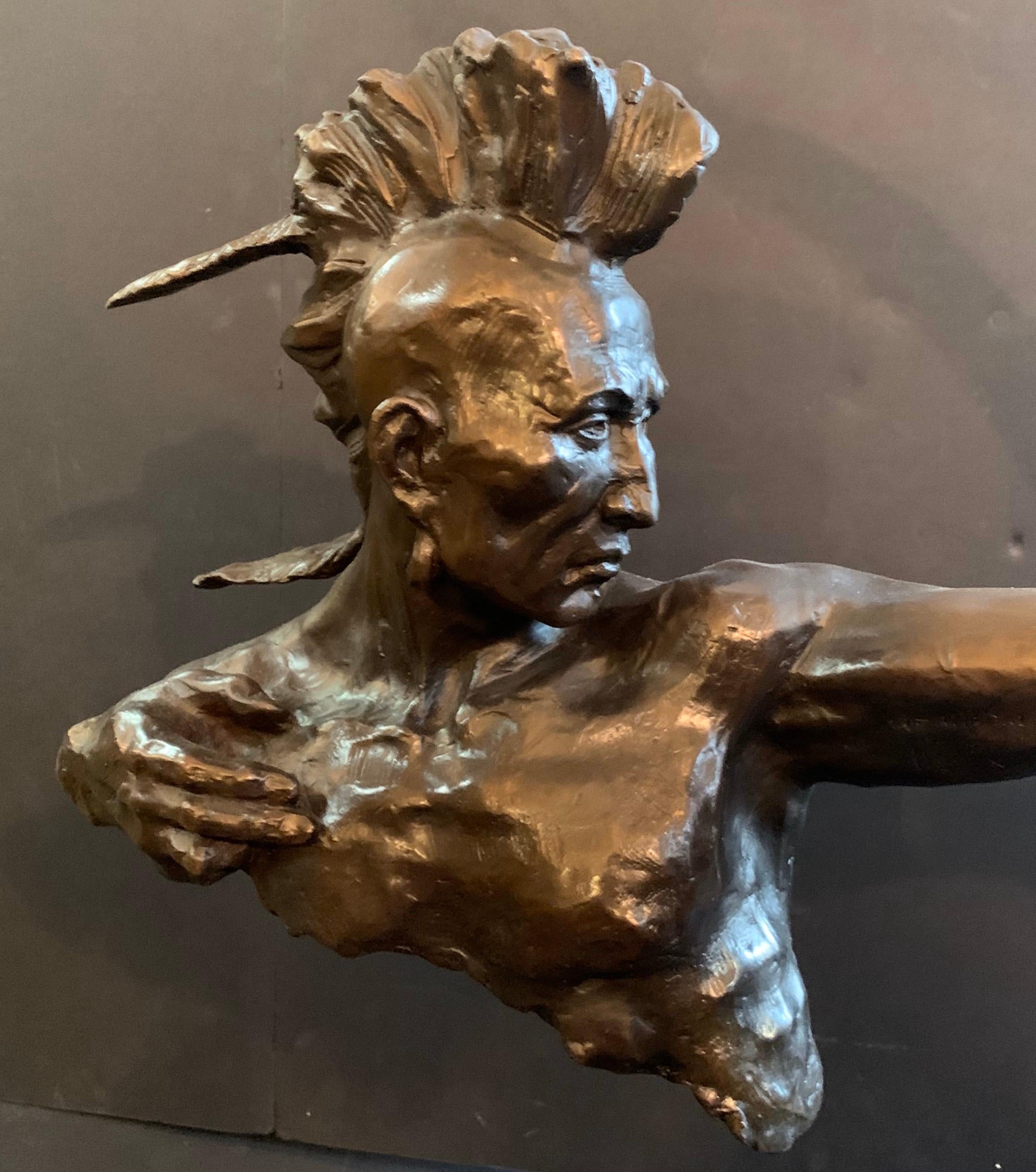 This is a stunning Art Deco stylized bronze of a Native American Indian male Archer with outstretched arm holding a bow that rests on a rectangular marble plinth. The Indian has a stern look on his face and has Mohawk styled hair. With the artist's