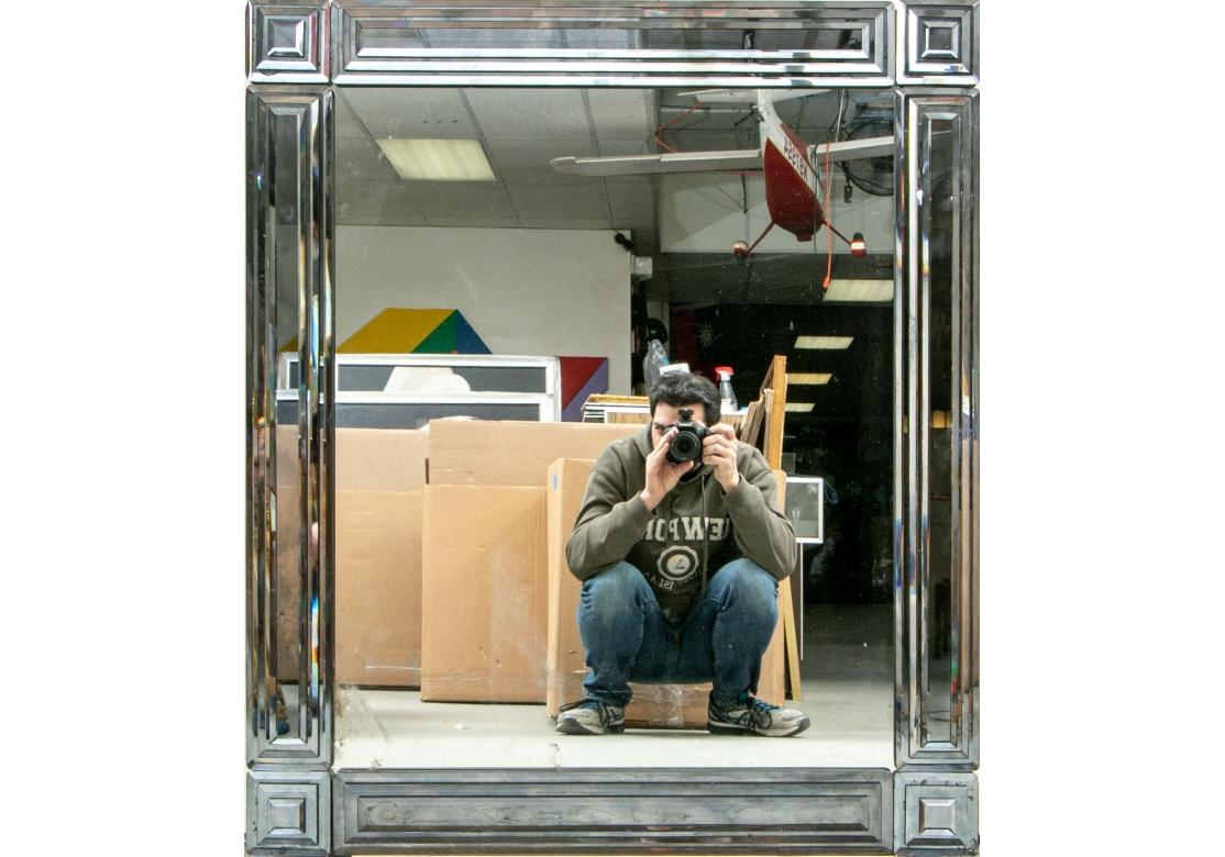A large and very fine wall mirror I. The Art Deco Style. The surround constructed of separate 3- D stepped sections for the corners and long panels in gray tone mirrors in the Art Deco manner. Mounted on wood backing. 
Measures: Height. 42 1/2