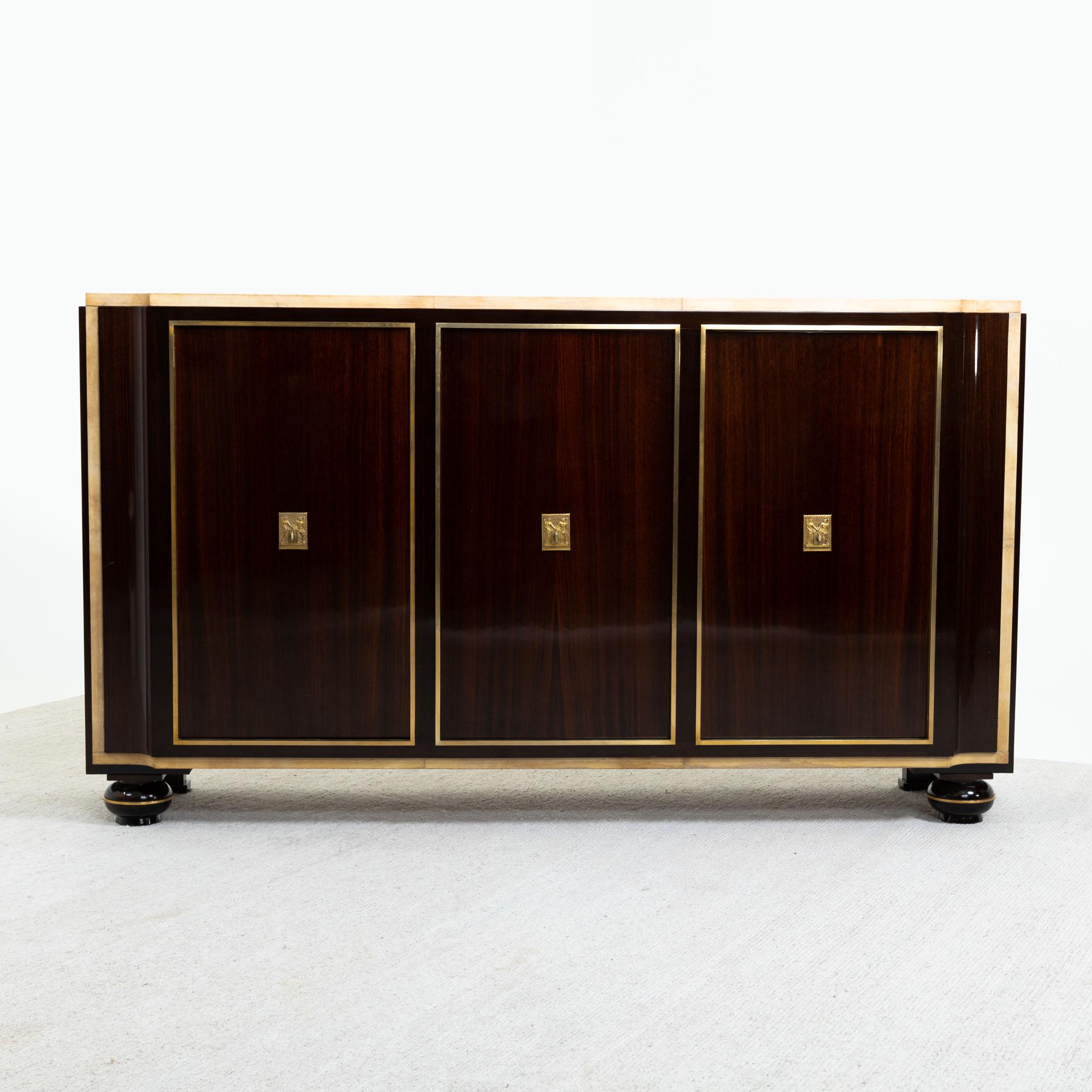 A fine Art Deco three door sideboard. 
Palisander with parchment top and details, brass escutcheons and details.
Side doors with shelving and middle section consisting of eight pull out drawers.