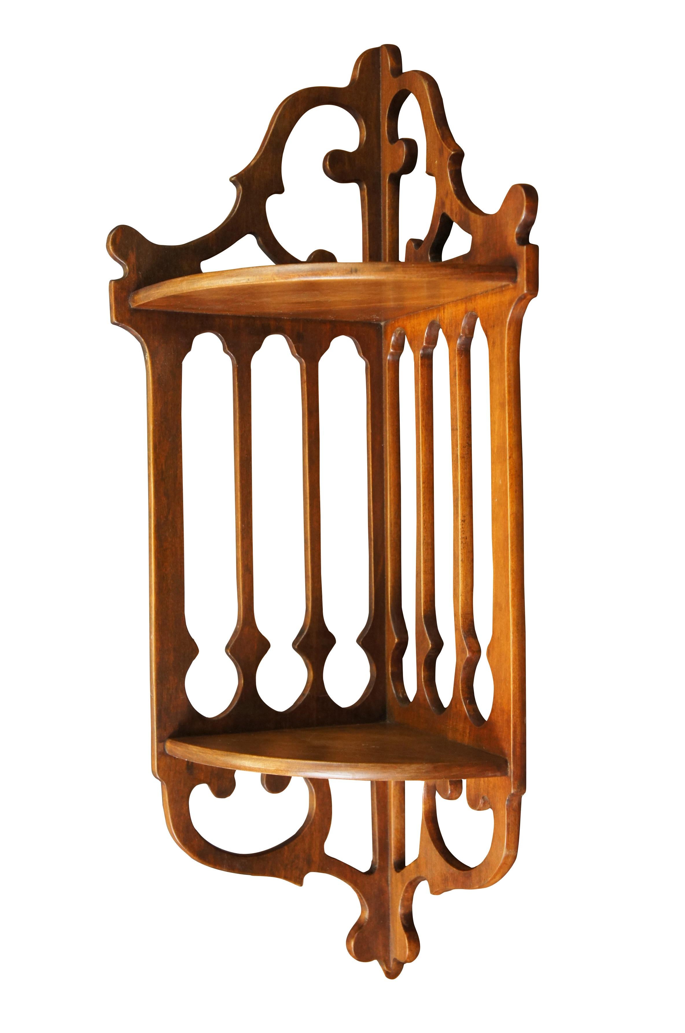 Mid 20th century two tier wall hanging corner shelf featuring Chippendale styling and pierced gingerbread type fretwork.  Attributed to Fine Arts Furniture Co - Grand Rapids

Dimensions:
10.25