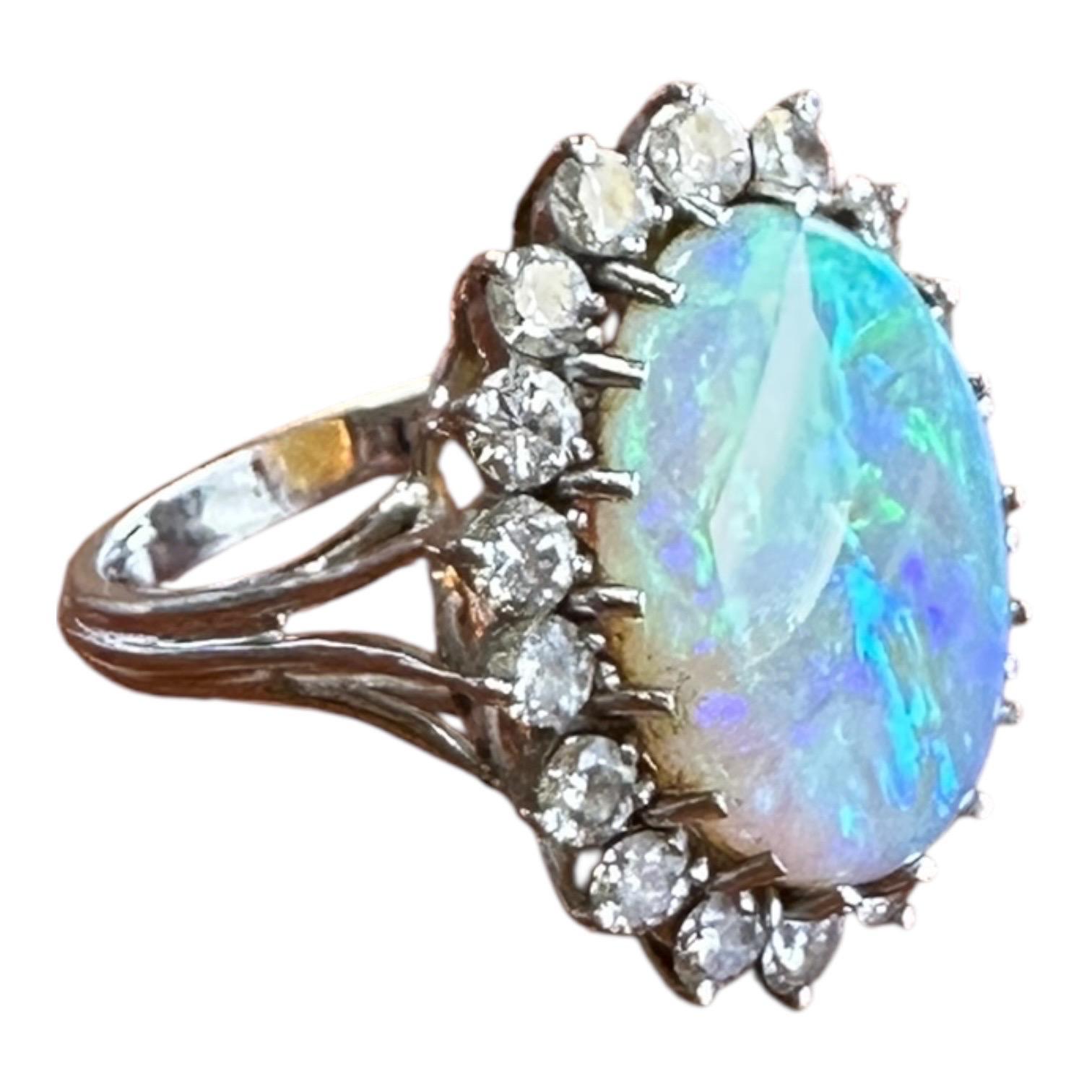 Questo raffinato anello in oro 14 carati ha come pietra principale una splendida opale di fuoco naturale, incastonata in una splendida forma ovale. L'anello è impreziosito da 18 diamanti scintillanti e da una montatura a griffe per una tenuta