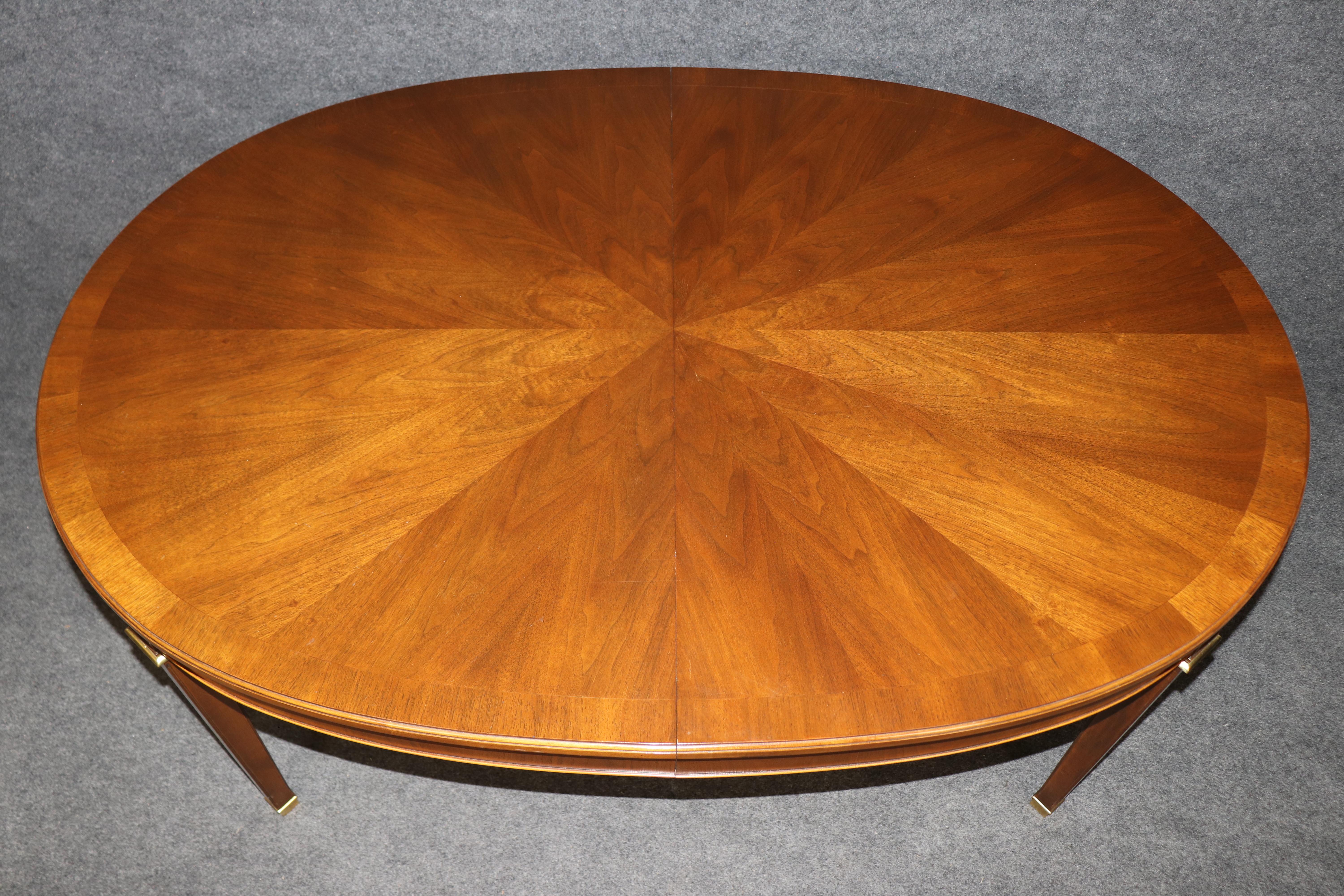 This is a fantastic Baker Furniture company French Directoire style cherry and brass oval dining table. The 1950s era table is in good original condition and has no major significant issues to speak of other than minor signs of age and use. The