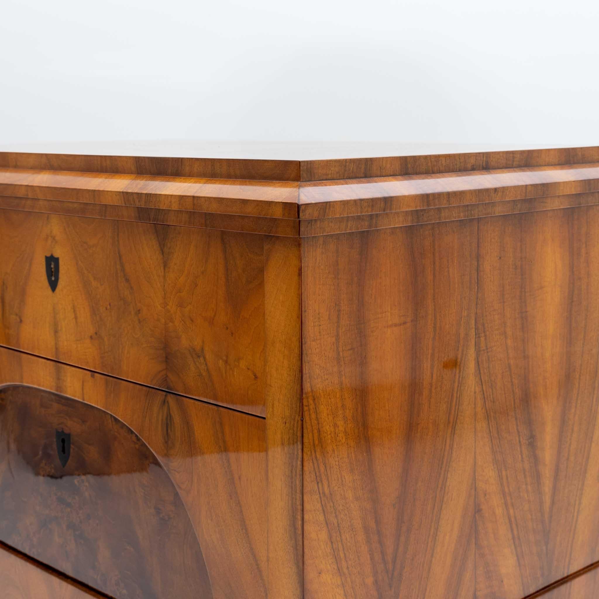 A Biedermeier chest of drawers in an architectural style.
Crafted in walnut veneer and walnut burl. 
Ebonized fruitwood drawer details.