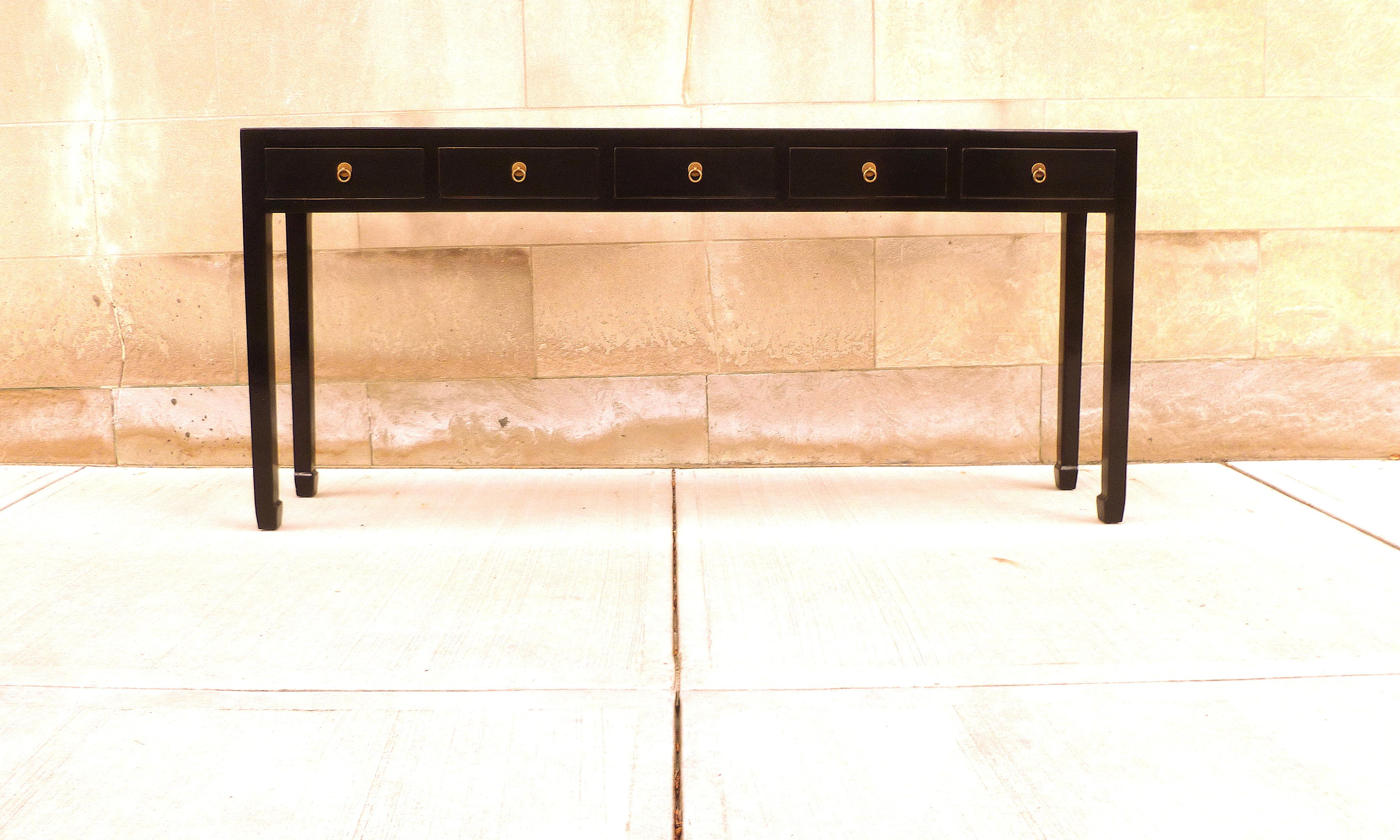 Élégante table console en laque noire avec cinq tiroirs, garniture en laiton. Une forme simple et une couleur magnifique. Nous proposons des meubles de qualité aux finitions élégantes, qui ont été publiés à plusieurs reprises dans les magazines