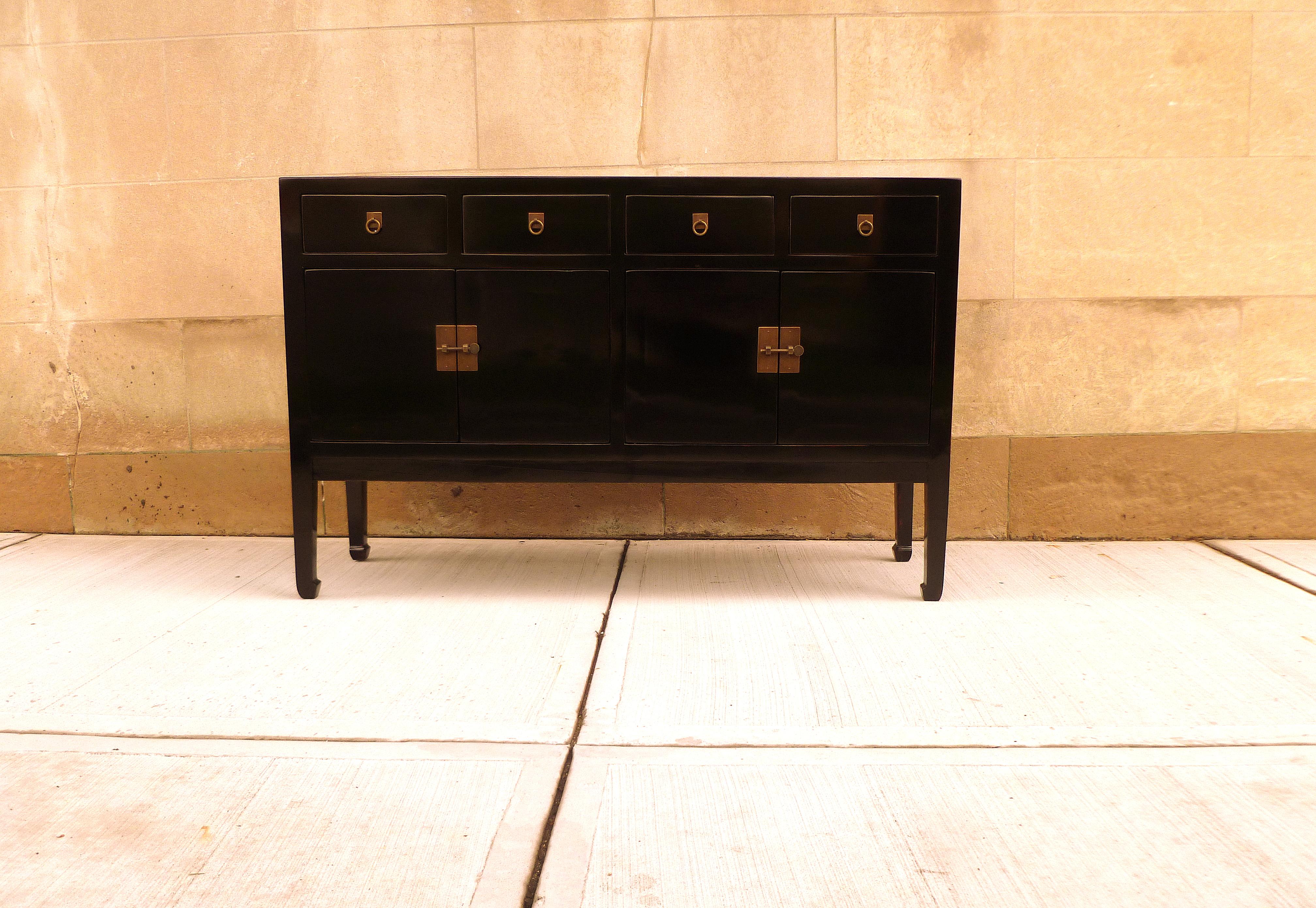 A refined and elegant black lacquer sideboard, framed top supported by square legs and joined by four drawers and two pairs of doors, brass fitting and ring pulls. We carry fine quality furniture with elegant finished and has been appeared many