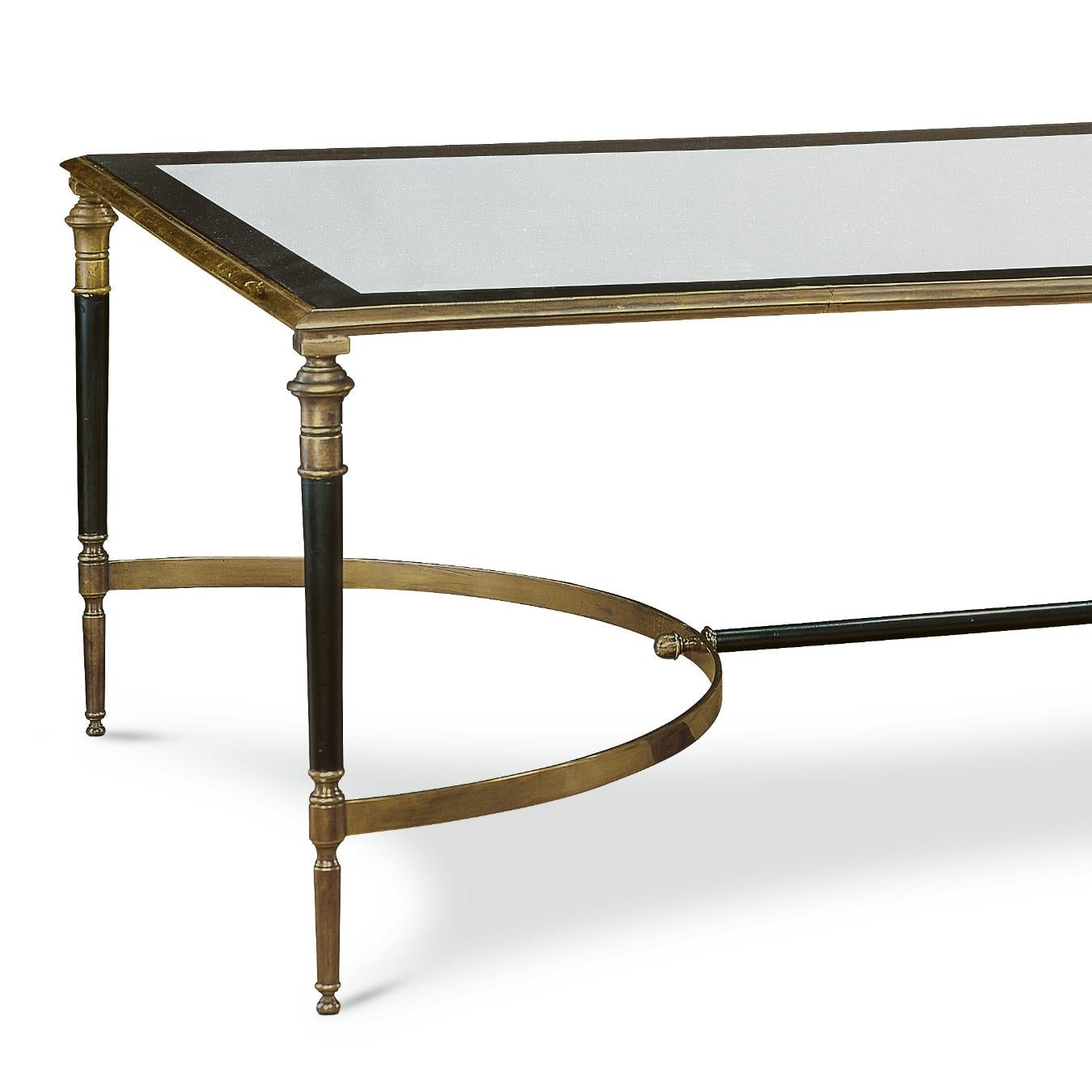 This finely constructed cocktail table has stunning brass frame and glass top. The legs are made of dark wood and brass with a symmetrical brass stretcher that rests beneath its surface.
   