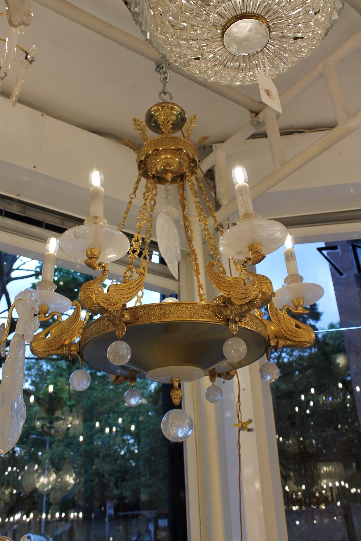 Un bellissimo lampadario dorato a 10 luci con 6 gocciolatoi esterni, ugelli e tubi per le candele, tutti in cristallo di rocca, ciascuno sormontato da cigni in bronzo fuso di eccellente qualità. Un piatto centrale termina con un piccolo piatto