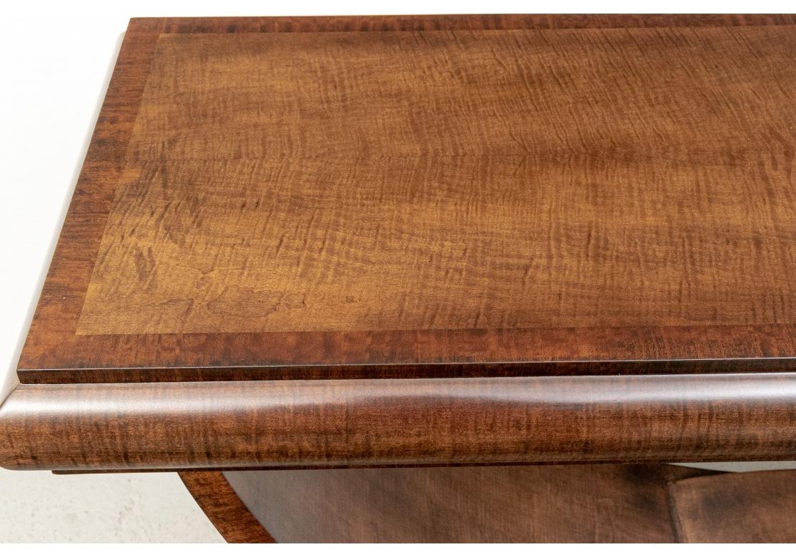 A contemporary console in a particularly attractive stained Burl in the Art Deco style. The banded top with a bull nose edge. Mounted on a wide U shaped support with center carved top. The base mimics the top and is raised on a shaped foot.