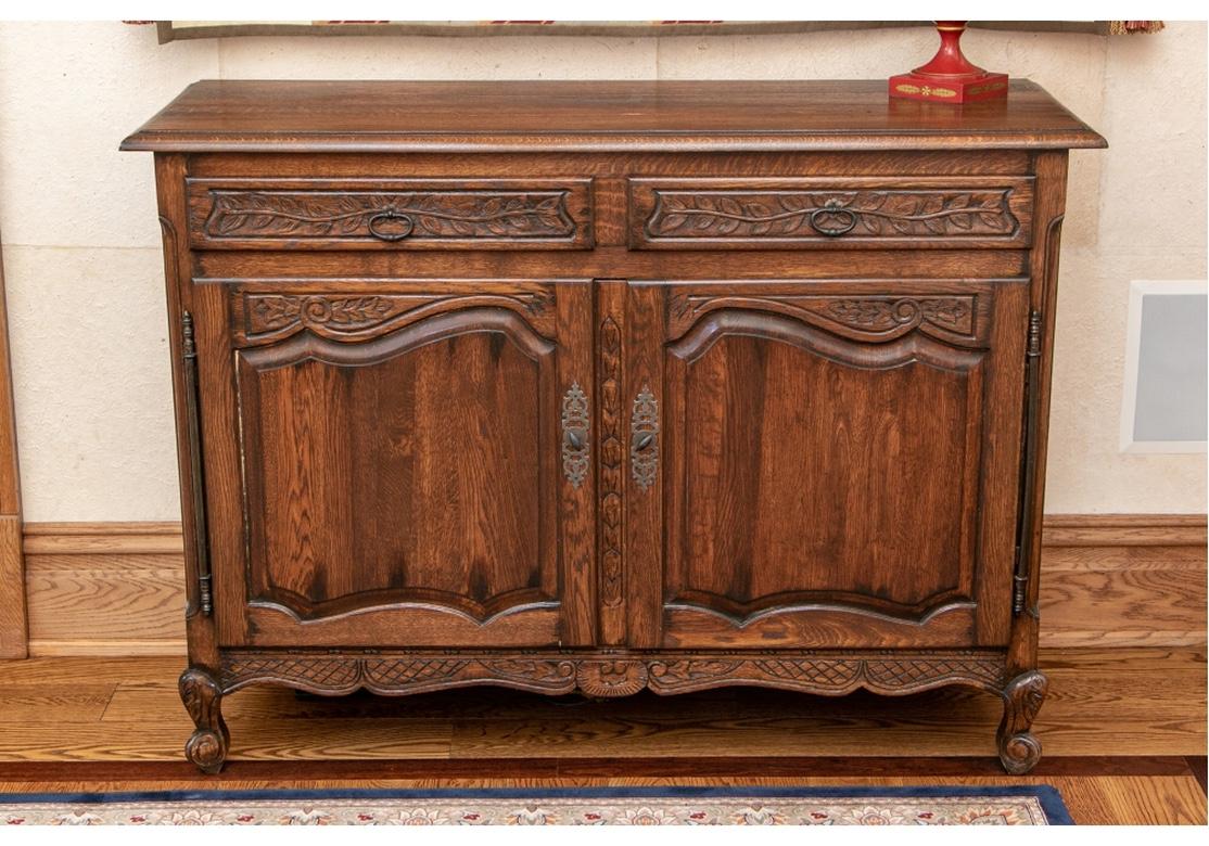 Country French server with two drawers with ring pulls above two raised panel cabinet doors with full storage. The server with scalloped apron and raised on whorled feet. A very pleasing deep stain and soft hand.
Dimensions: 20