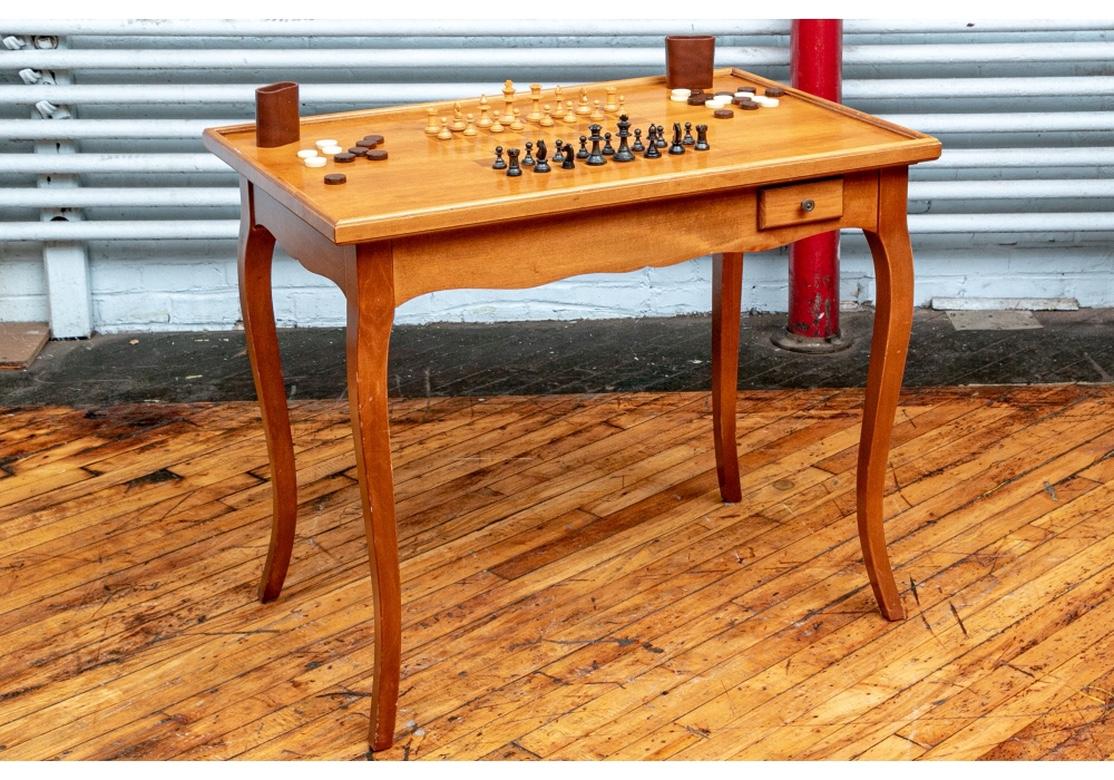 A finely crafted French style games table with 3/4 gallery on the banded top. With a short apron drawer on the front and back sides. The top has a Chess board underneath and is removable to reveal a backgammon board. Raised on tall cabriole legs.