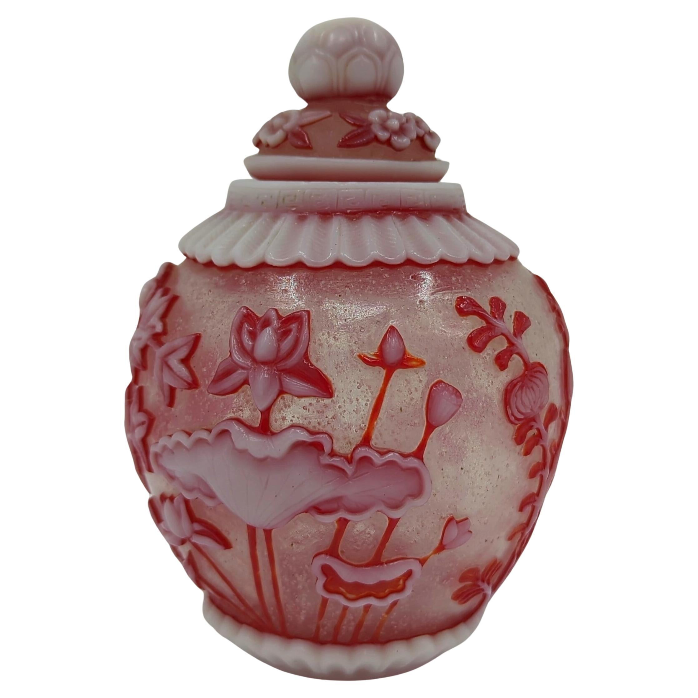 Presenting a fine three-color glass overlay covered jar, meticulously crafted in an ovoid form. The piece features a harmonious blend of milk white and ruby red glass overlay on a snowstorm ground, a technique that showcases the artisan's mastery