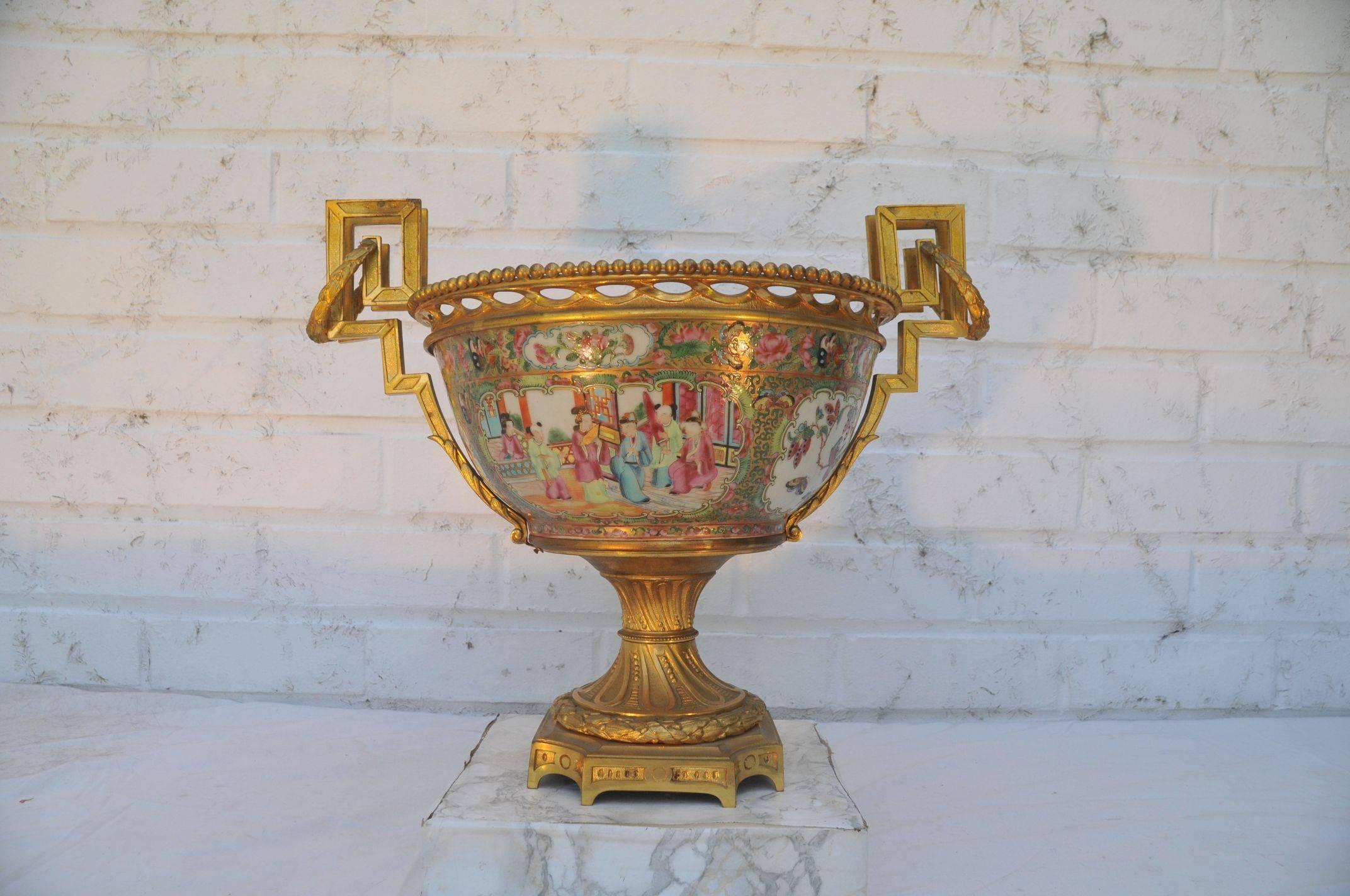 A fine canton ormolu-mounted garniture.
19th century.
Comprising a central bowl and two ormolu vases.
The bowl decorated in bright enamels with a central medallion surrounded by four shaped reserves of figures in an audience scene before a