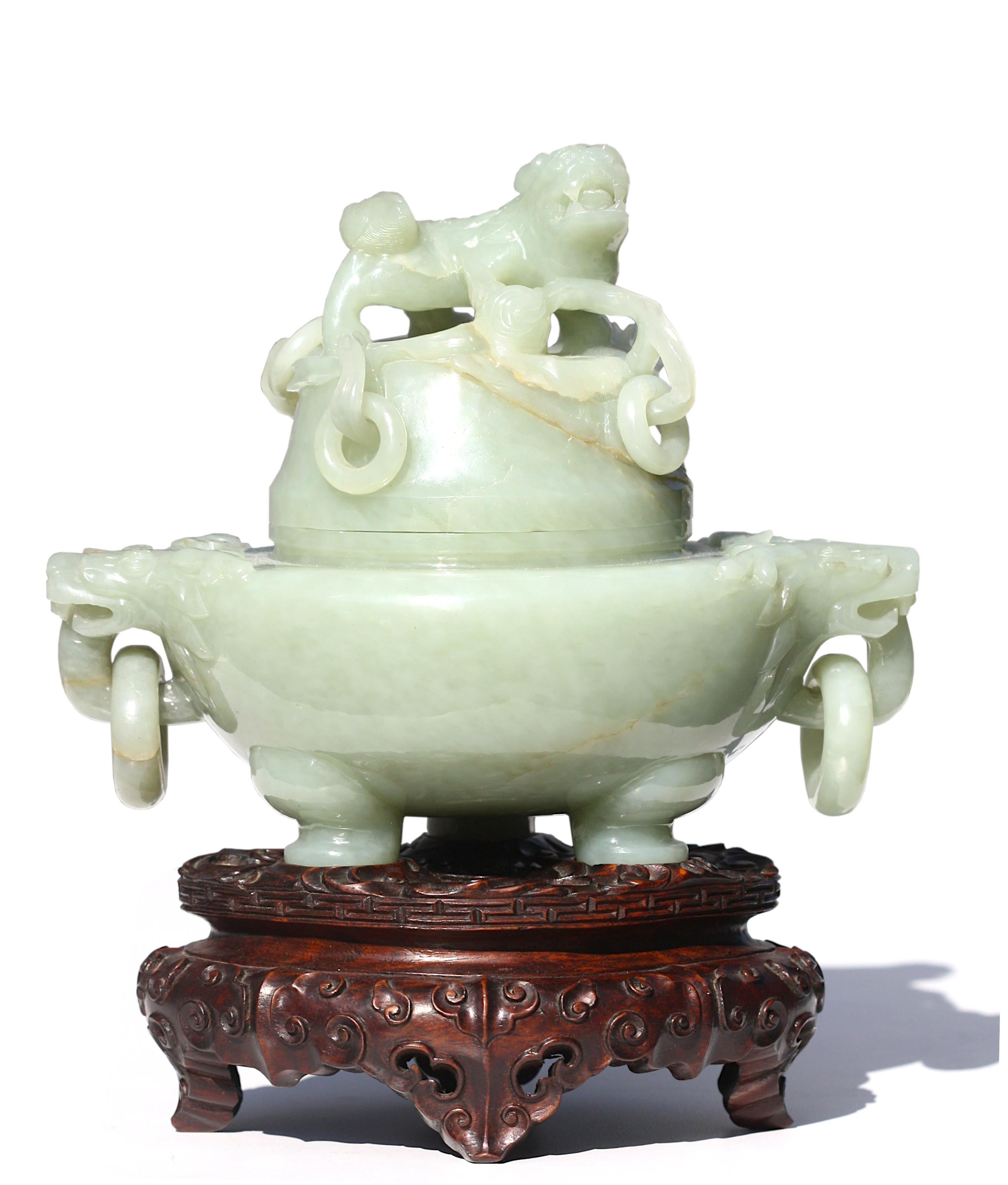 Fine Chinese Celadon Jade Tripod Censer
Qing Dynasty
The compressed body with a raised rim and flanked by a pair of reticulated mythical-beast handles suspending loose rings, on tripod stylized paw feet, the cylindrical cover with reticulated faux