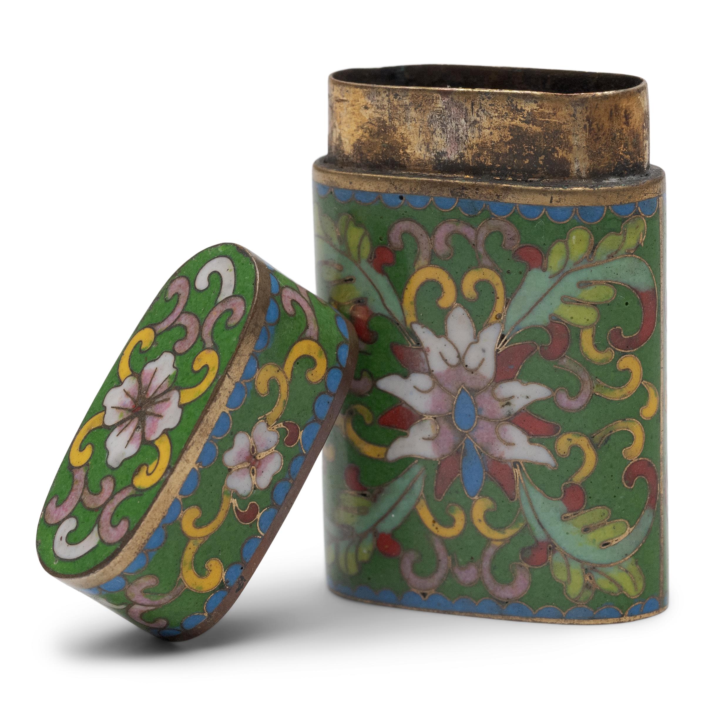 This petite cloisonné box is a pocket-sized canister once used to store a smoker's personal supply of opium paste. Providing an airtight seal, the box is finely decorated with an abstract floral design in bright enamels against an emerald green
