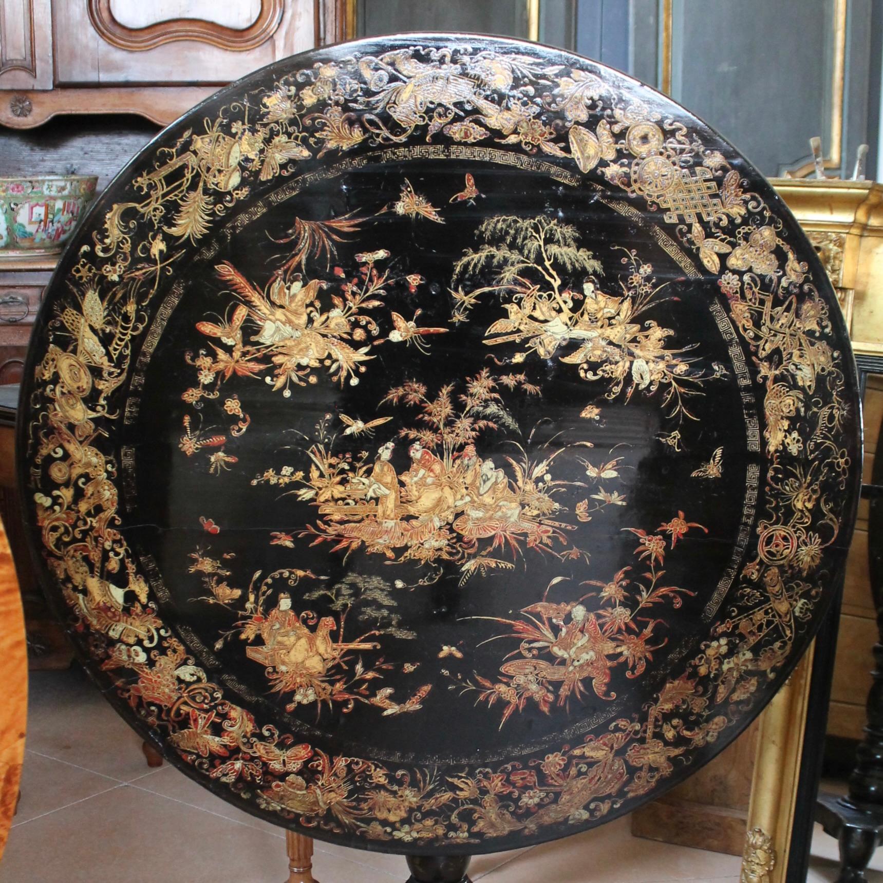 A fine early Chinese lacquer tilt top table decorated with stunning painted and gilded vignettes. There are all manner of elegantly executed sacred objects and musical instruments arrayed in the border around the top, in Chinese red with gilt