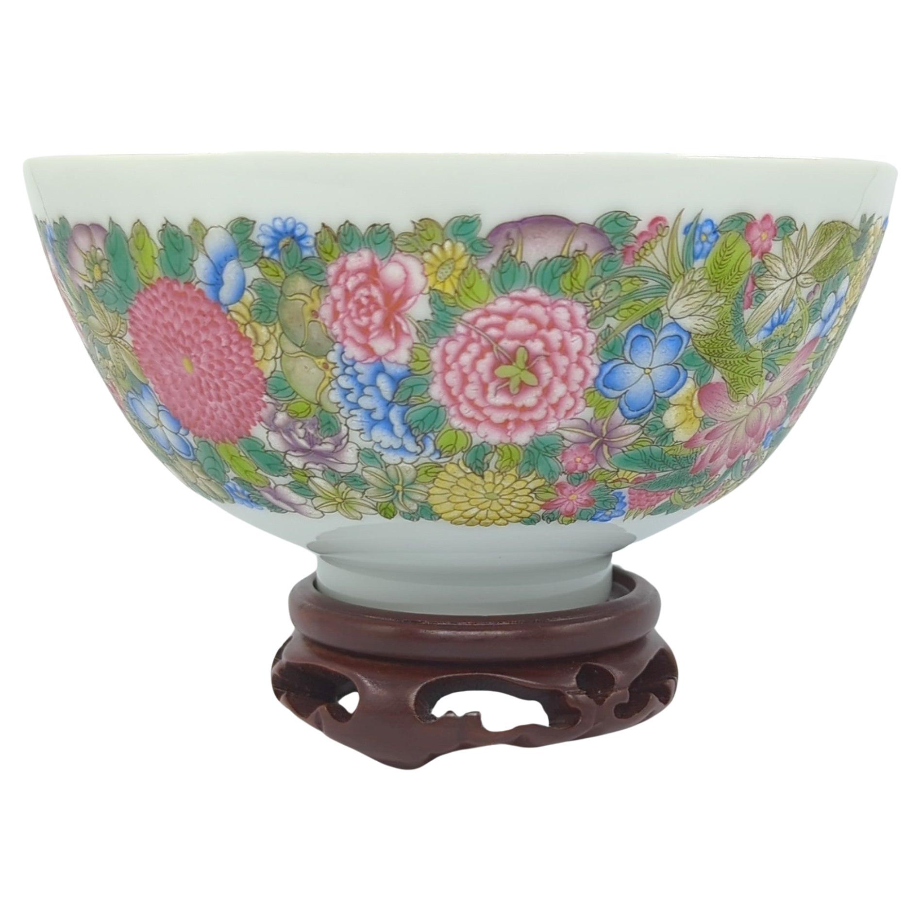 This finely decorated Chinese porcelain bowl is a stunning example of 20th-century craftsmanship, embodying both artistic mastery and cultural significance. The bowl is adorned with a vibrant band of mille fleur flowers on the exterior, a design