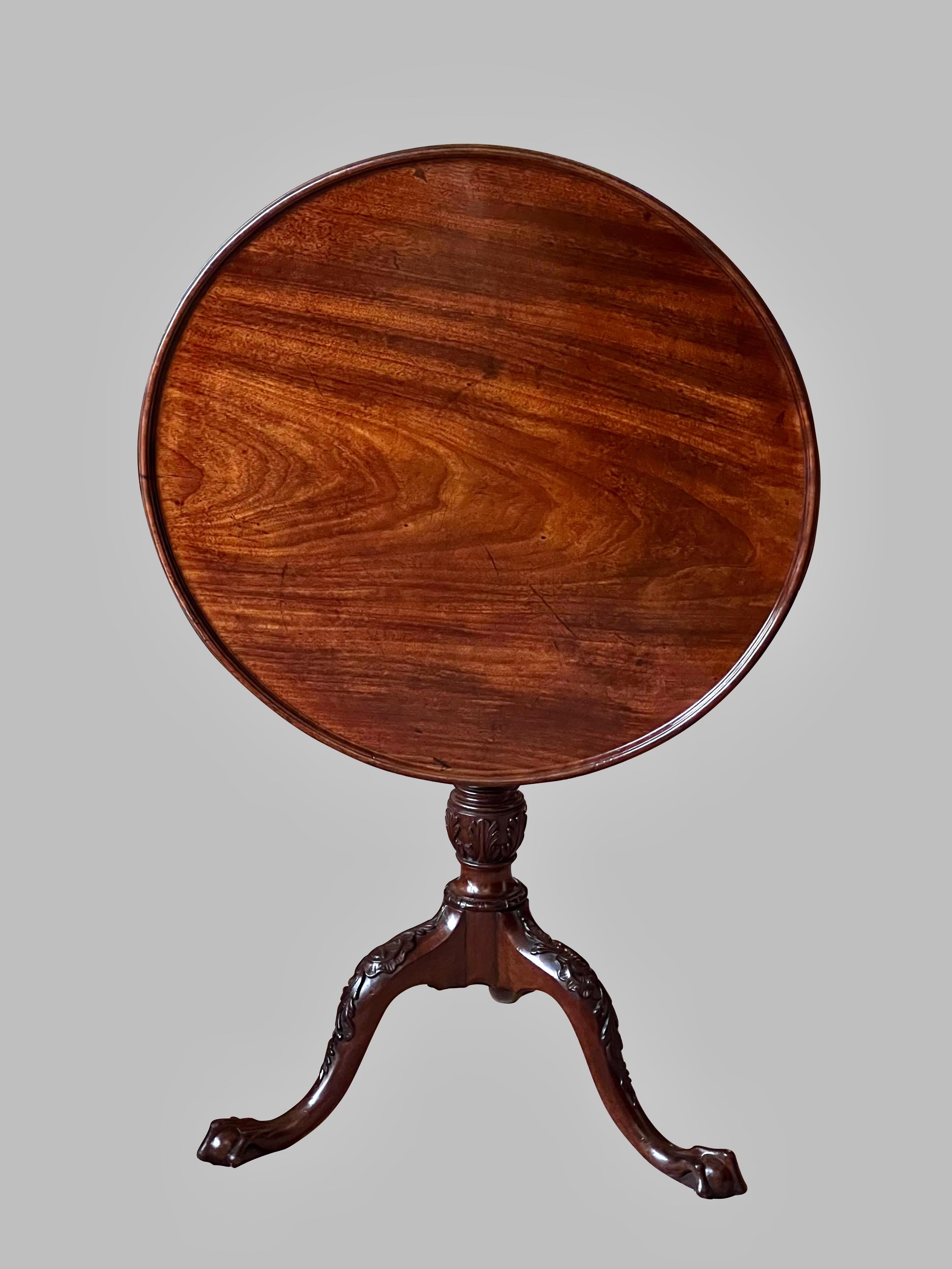 A fine Chippendale period mahogany tilt-top table, the single board top with a dished edge, supported by a beautifully carved standard, with fluting and cartouches, resting on a tripod base with acanthus carved legs ending in ball and claw feet.