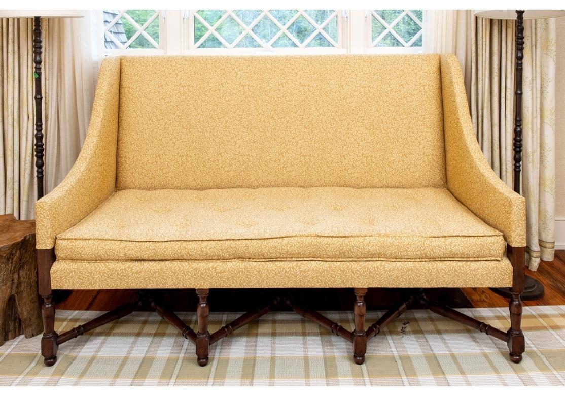 Custom upholstered settee with sloping and flared arms, the back and arms raised above the seat (see photo 9). With a fabric covered apron, button tufted shallow seat cushion, upholstered with foliate vines patterned fabric, raised on a triple