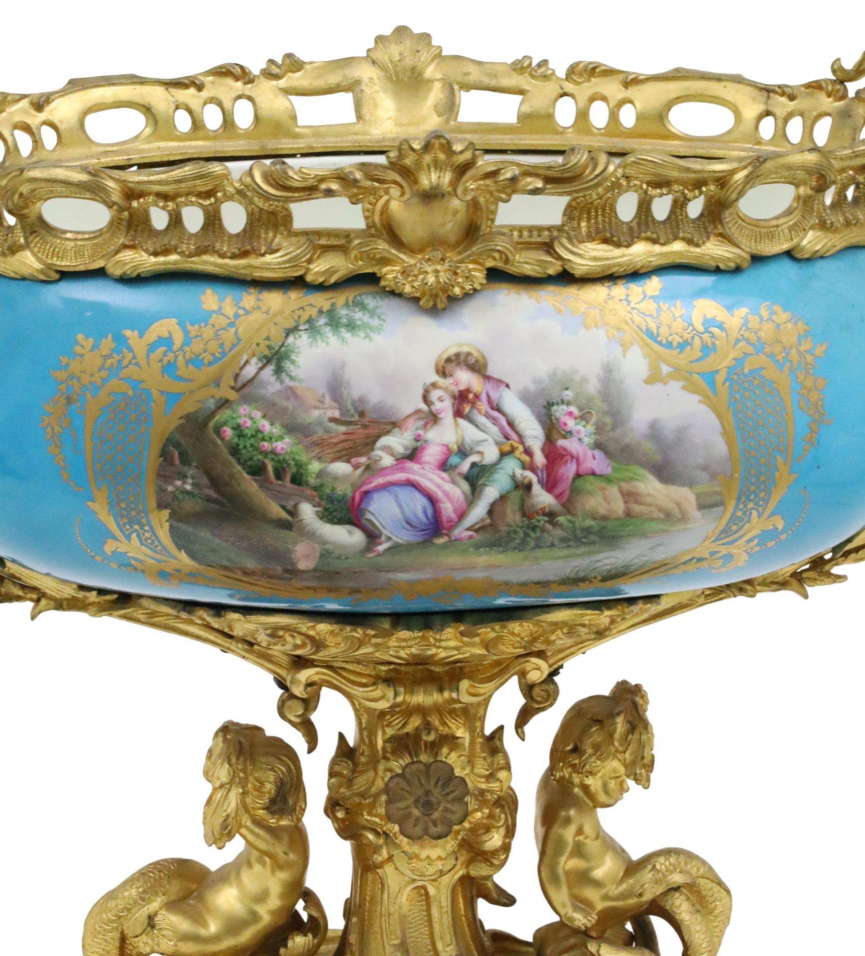 World class Sevres Style robin egg blue porcelain centerpiece having hand painted courting scene reserves, mounted in finely casted dore bronze with six outstretched candelabra arms and resting on rocaille plinth surmounted by dolphin cherubs, late