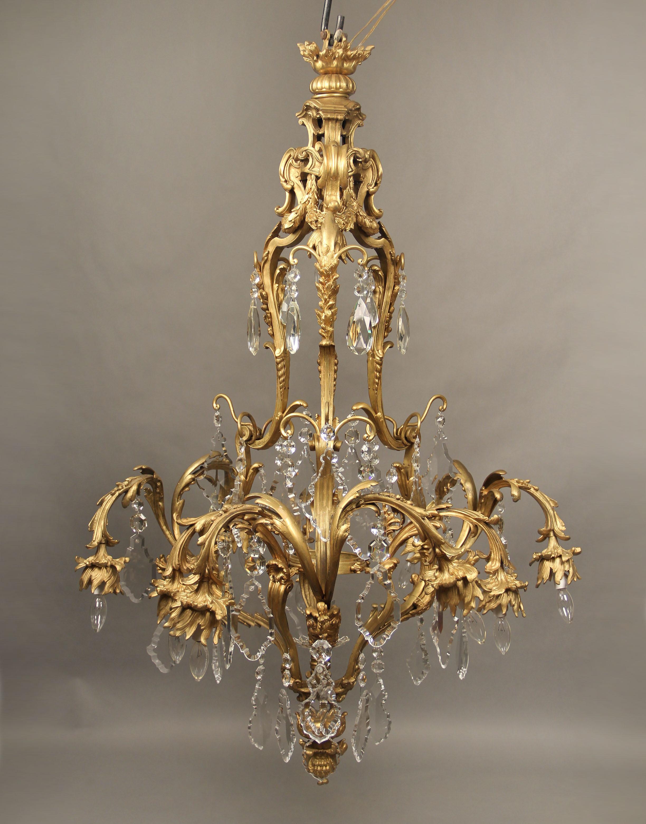 A fine early 20th century gilt bronze and crystal eleven-light chandelier

A bronze casted cage, designed with three male masks, flowers, shells and reefs, with multifaceted and shaped crystals, nine perimeter and two interior lights.

If you