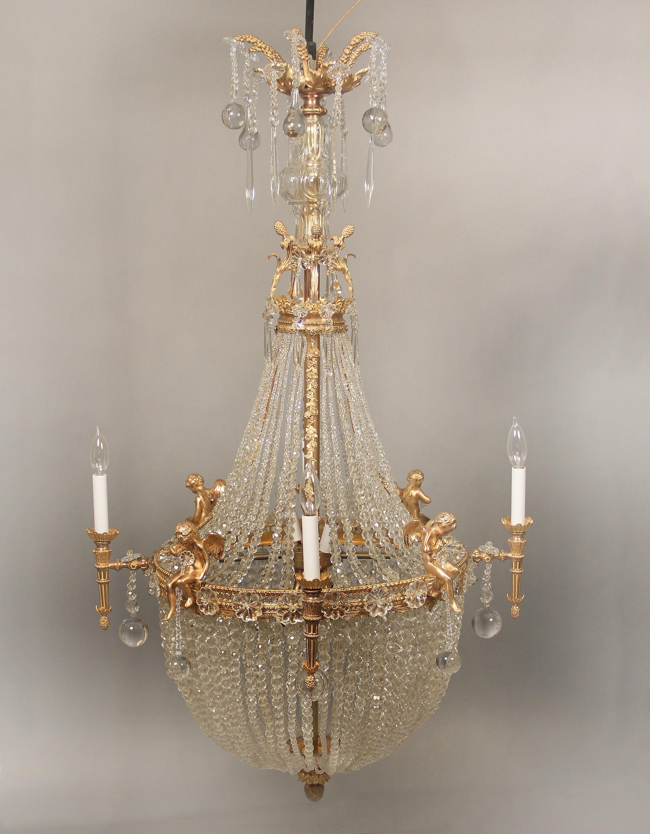 A fine early 20th century gilt bronze and crystal ten-light basket chandelier

The gilt top with bronze berries and drop crystal balls, cut crystal central column leading to beaded strings and bronze flowers running down to the basket, the body