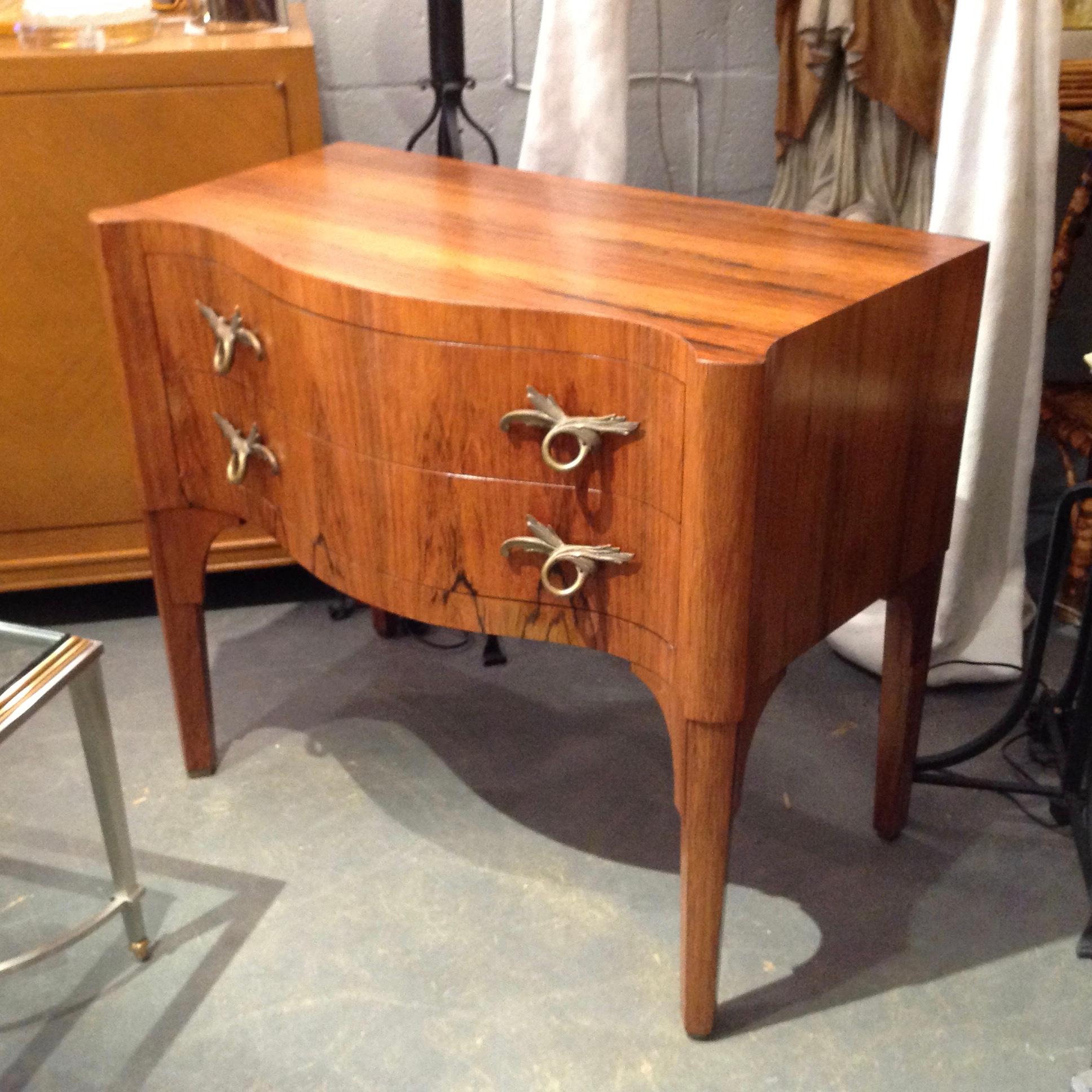 Superb quality signed by the maker. Fashioned with exquisite rosewood veneers and serpentine front.
The petite commode is appointed with stunning doré hardware.
