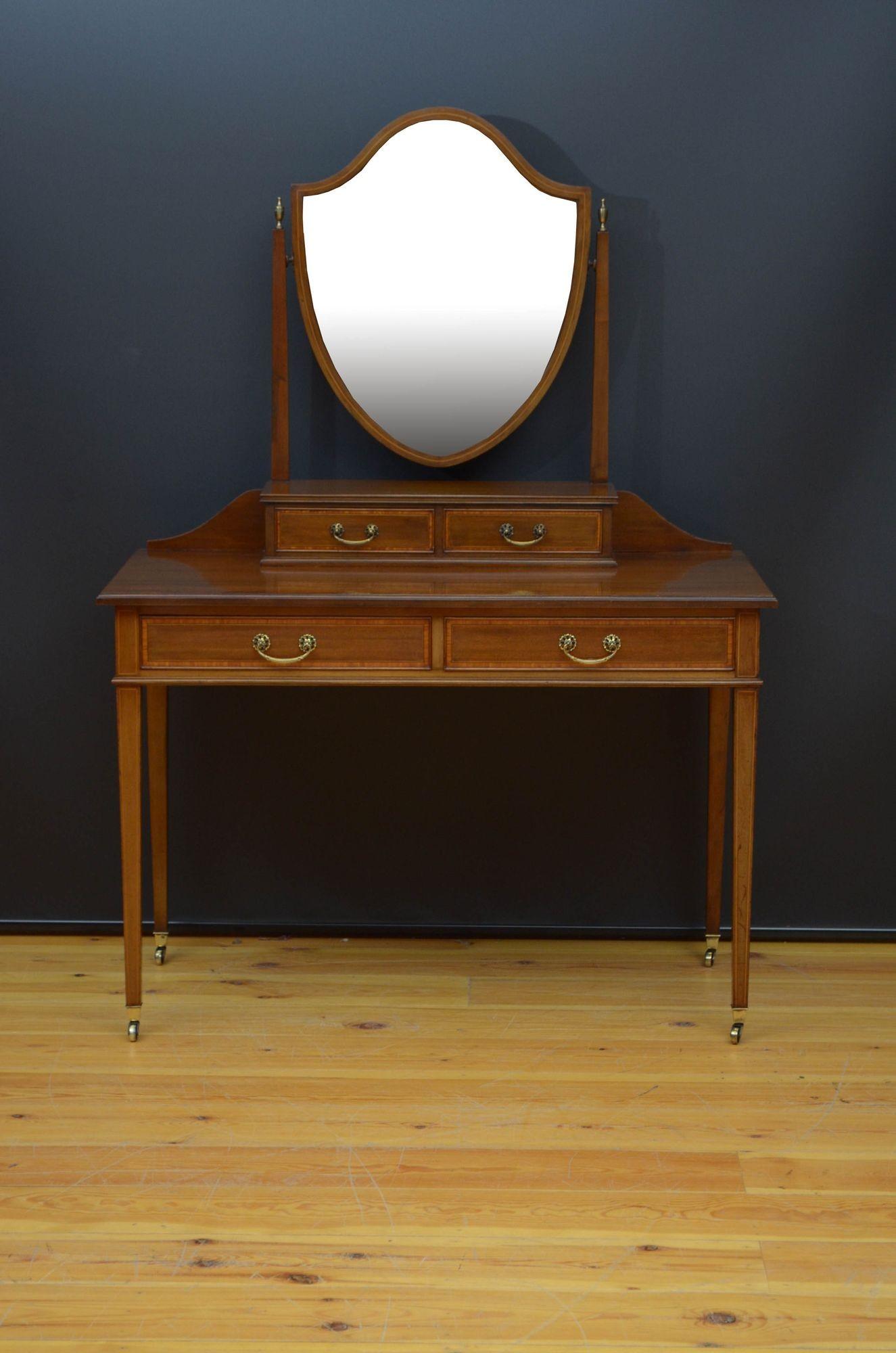 R025 Fine and elegant Edwardian mahogany dressing table, having original bevelled edge mirror with minor foxing in shield shaped frame on slender supports with decorative brass urns above two jewellery drawers and figured mahogany top with moulded