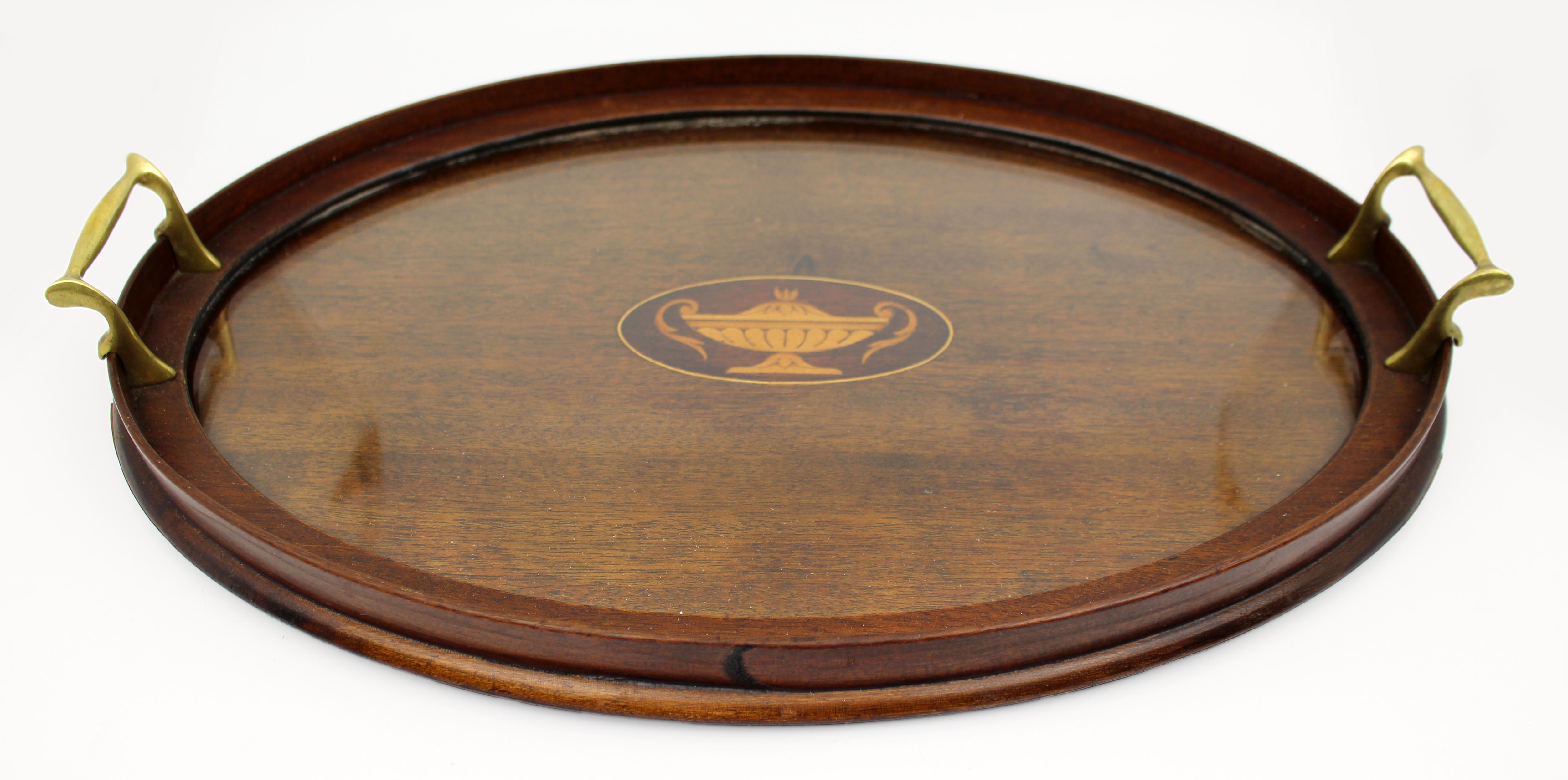 Vassoio ovale intarsiato in mogano e legno di raso, Inghilterra, circa 1900
Elegante vassoio da portata ovale dei primi del Novecento in mogano massiccio, caratterizzato da un raffinato motivo di urna neoclassica intarsiata in legno di raso al