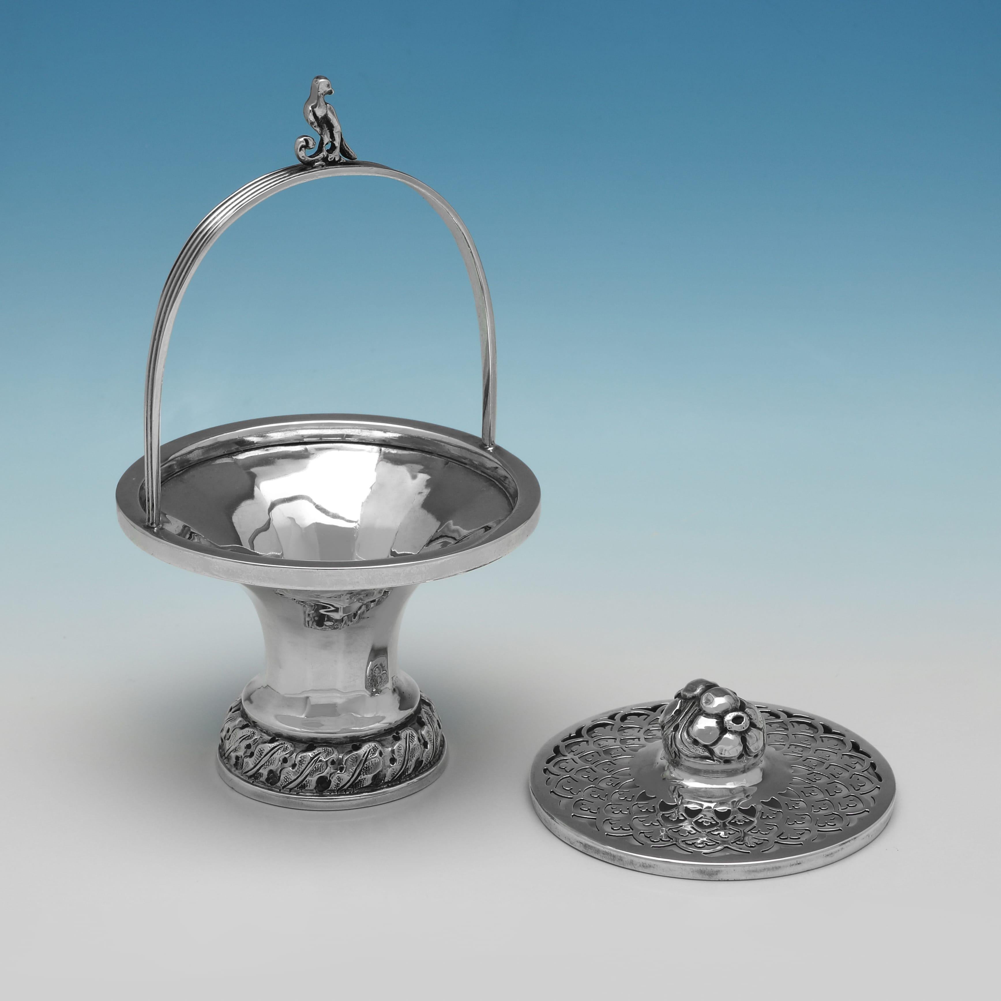 Marchiato a Sheffield nel 1910 da Sharman D. Neill Ltd., questo antico portavaso in argento sterling impreziosito presenta un coperchio traforato sormontato da un fiore, con un manico oscillante sormontato da un motivo a volute e uccelli. La base a