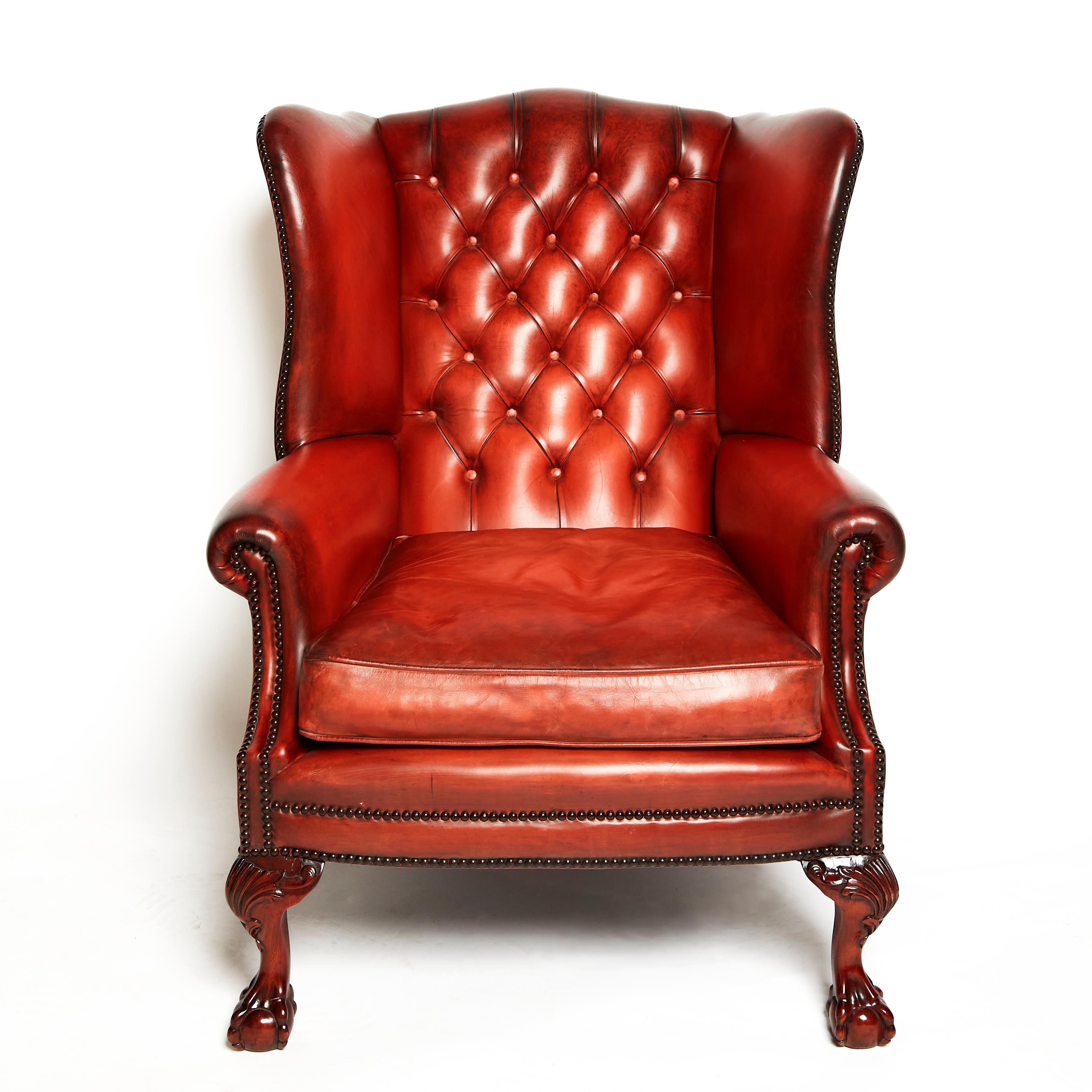 Ce fauteuil à oreilles en cuir anglais de très belle qualité et fabriqué à la main est doté d'un piètement à boules et griffes dans le style du XVIIIe siècle. Il est doté d'un dossier à boutons et d'une assise à coussins séparés, fabriqués selon les