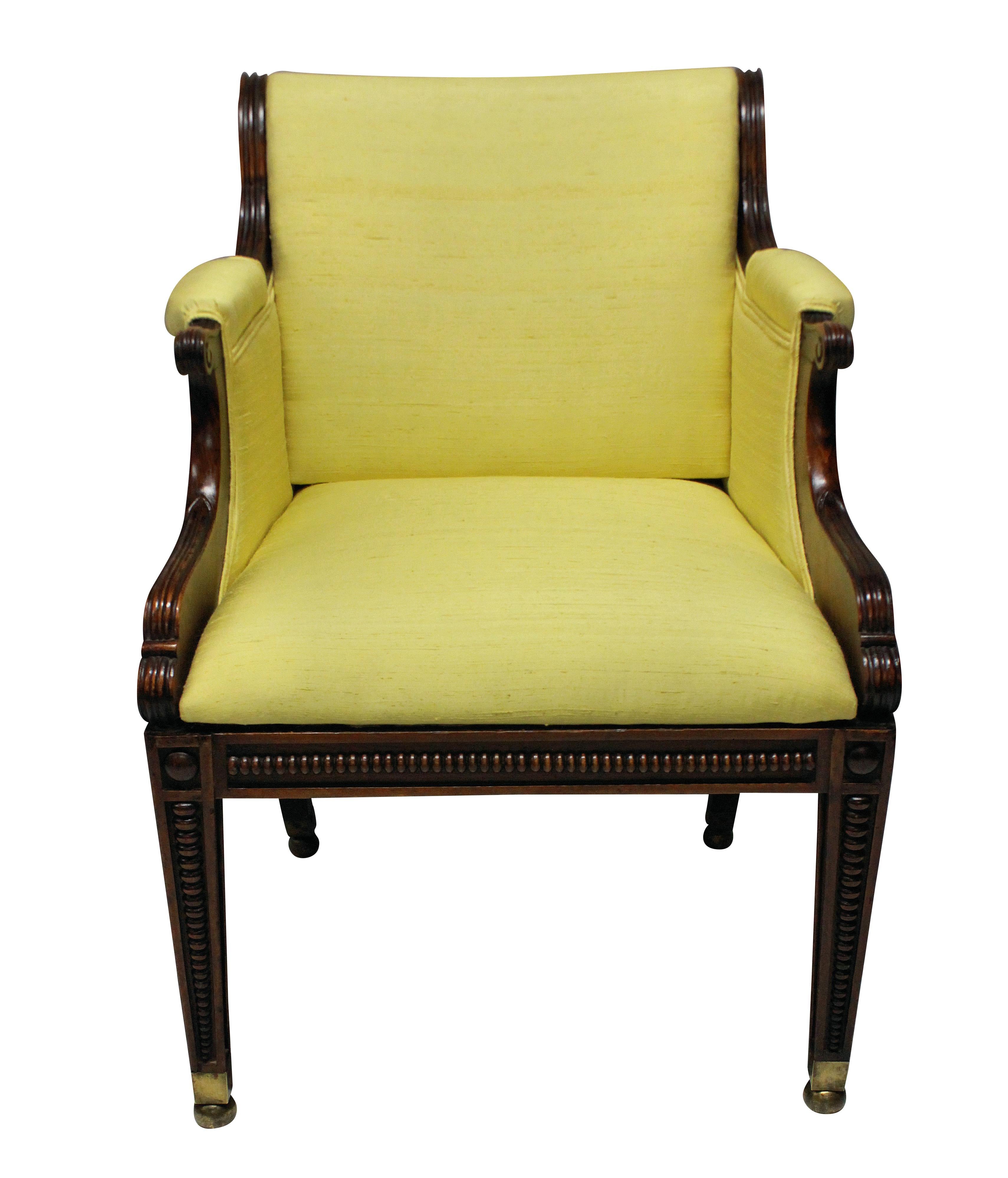 A fine English faux rosewood library chair of unusual design, with graduated tapering spheres down the legs, with brass ball feet. Newly upholstered in pale yellow silk.