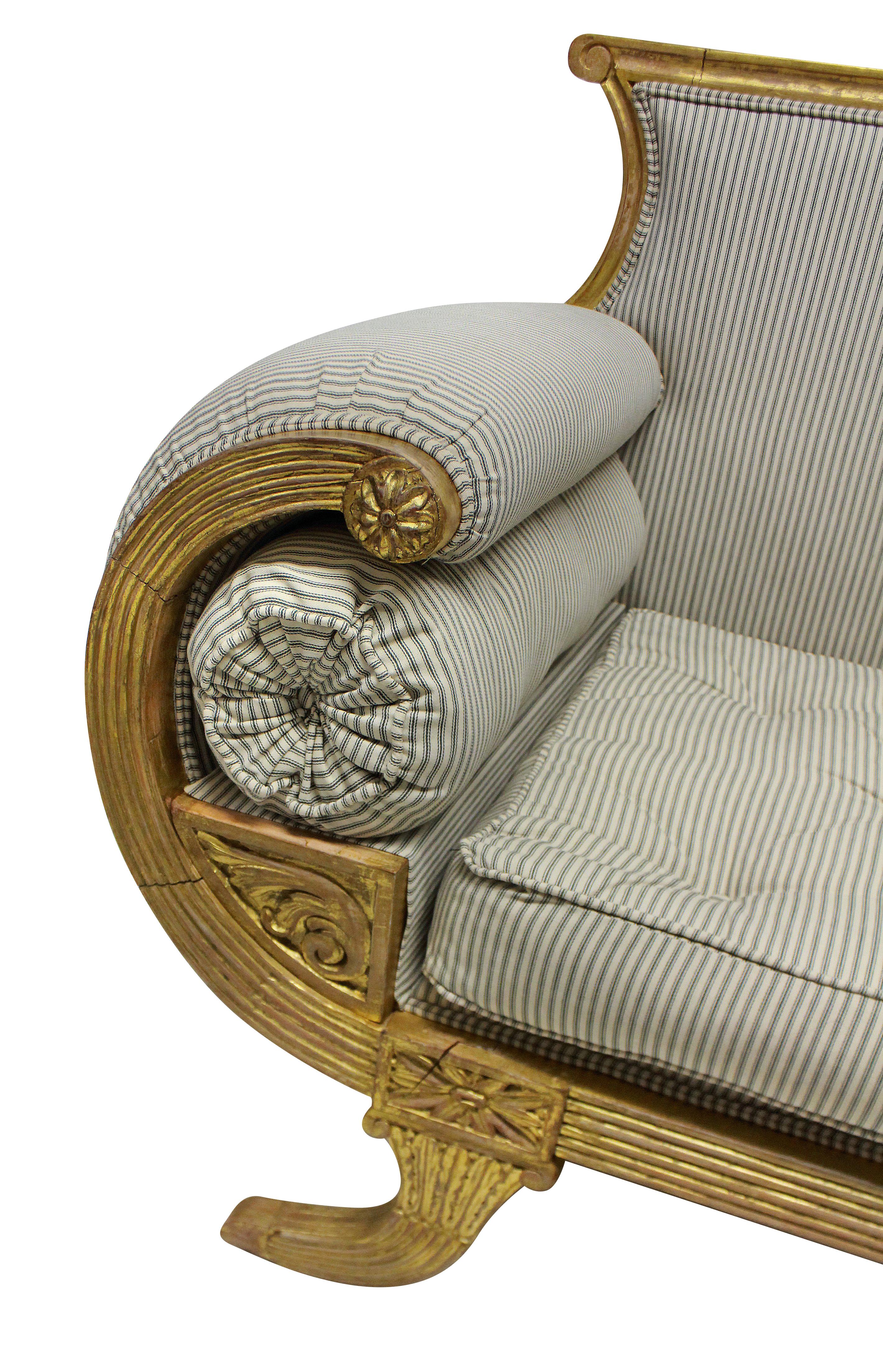 A fine English Regency revival giltwood settee in the Egyptian taste. Water gilded throughout and upholstered in ticking.