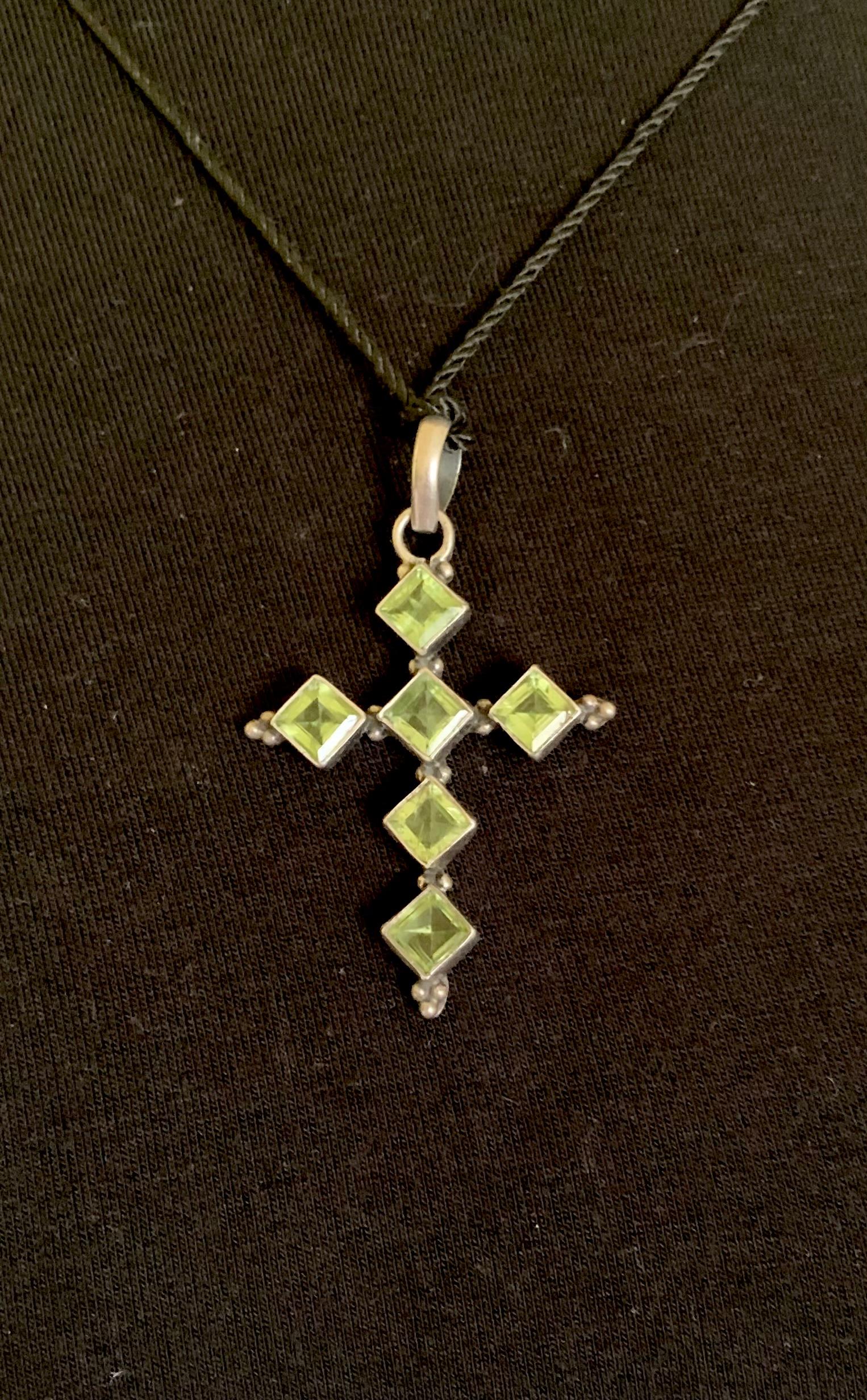 Beautiful Arts and Crafts style sterling silver and peridot cross featuring six rhombus shaped square cut 5mm by 5mm peridot gemstones. Peridots have a rich history dating back to ancient Egypt. They were associated with  having protective qualities